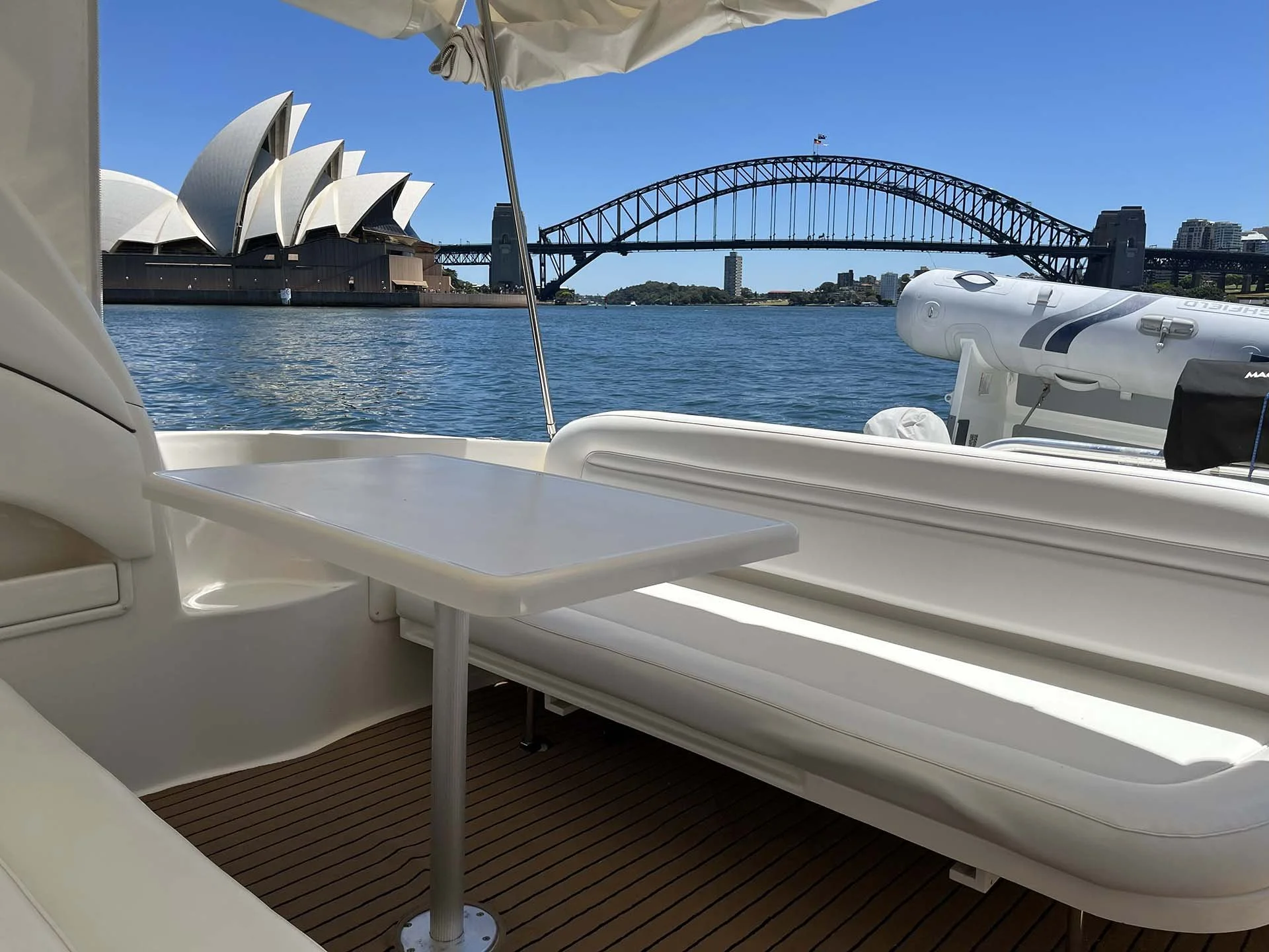 View from a boat showing the Sydney Opera House and Harbour Bridge on a sunny day.