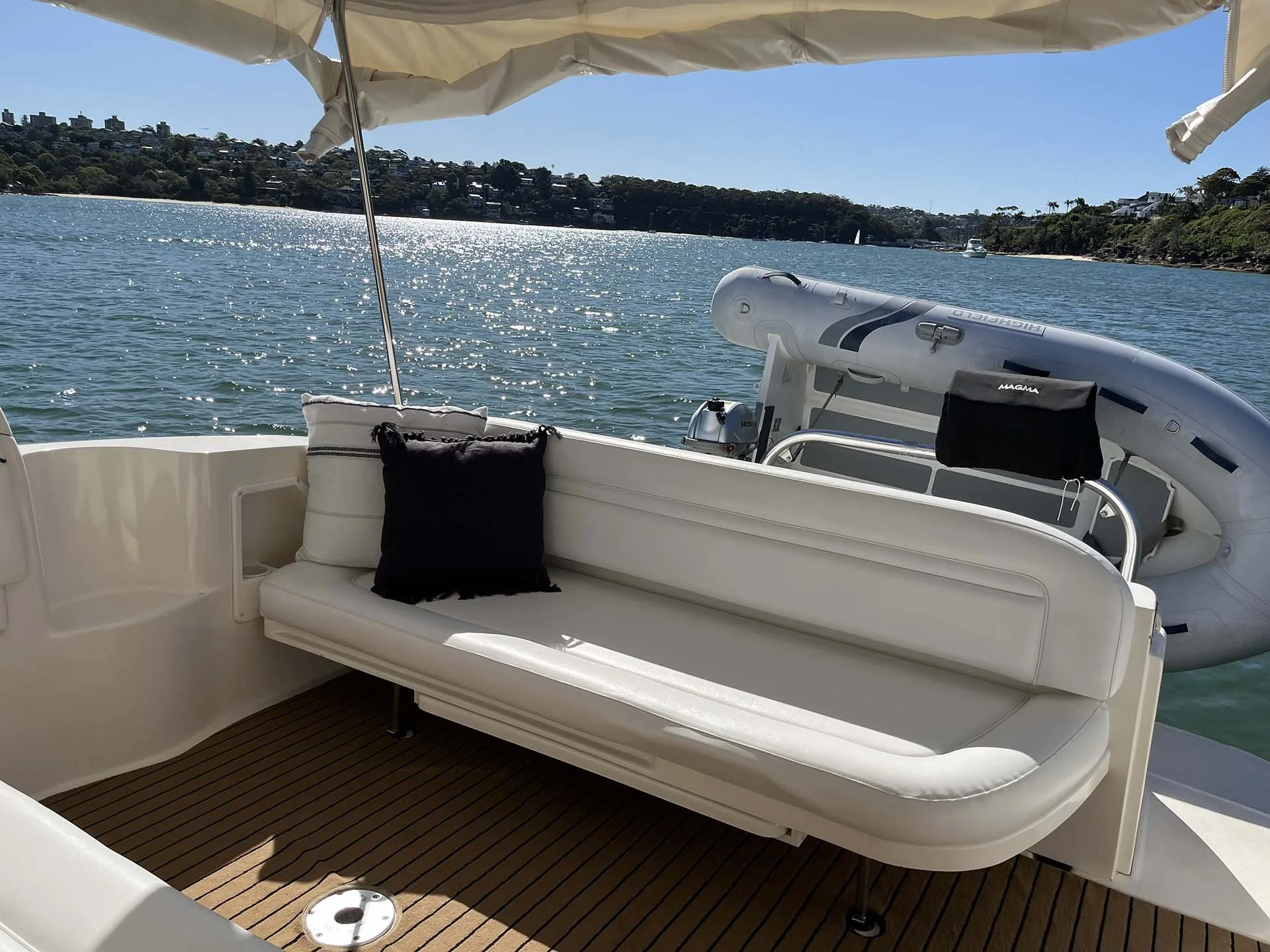 Opal on a body of water with a hillside and houses in the background under a clear blue sky.