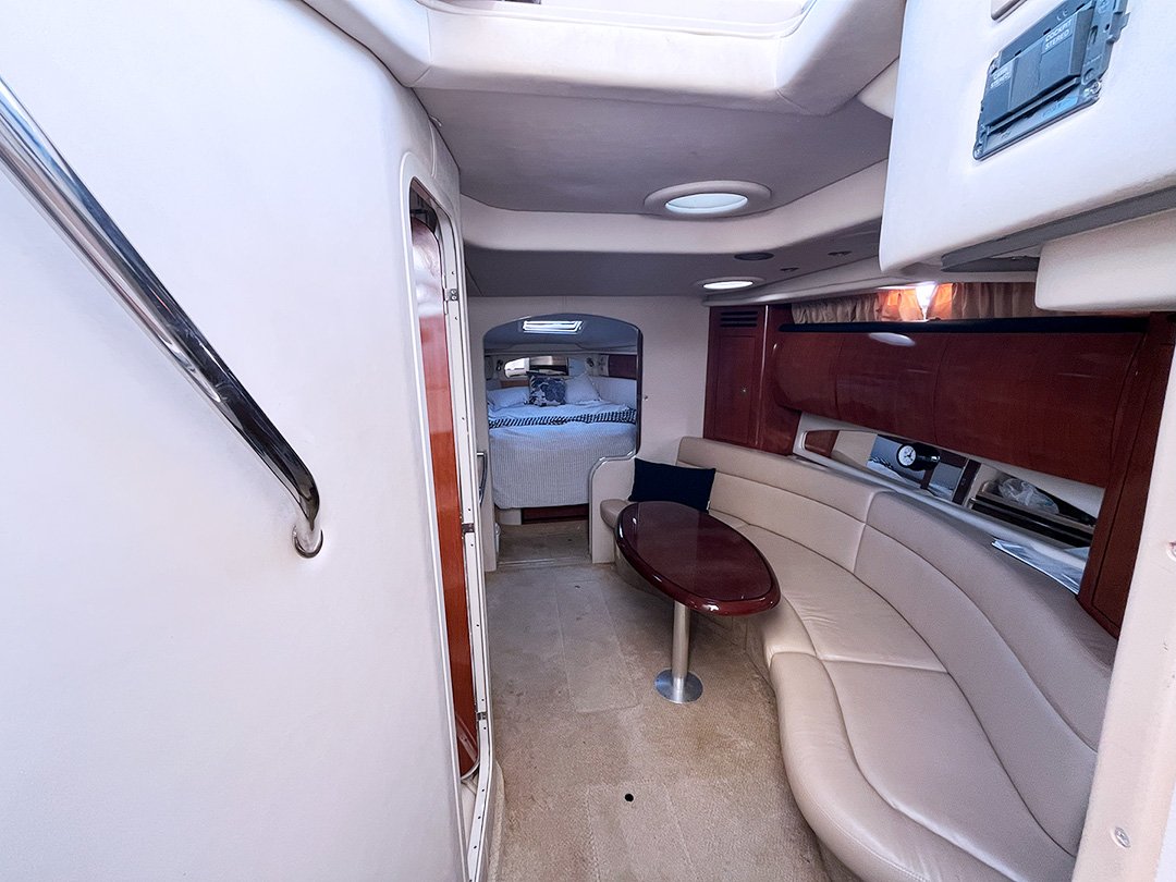 Interior of Opal with curved beige leather seating, small wooden table, a cushion, and a sleeping area with a bed and pillows visible in the background.