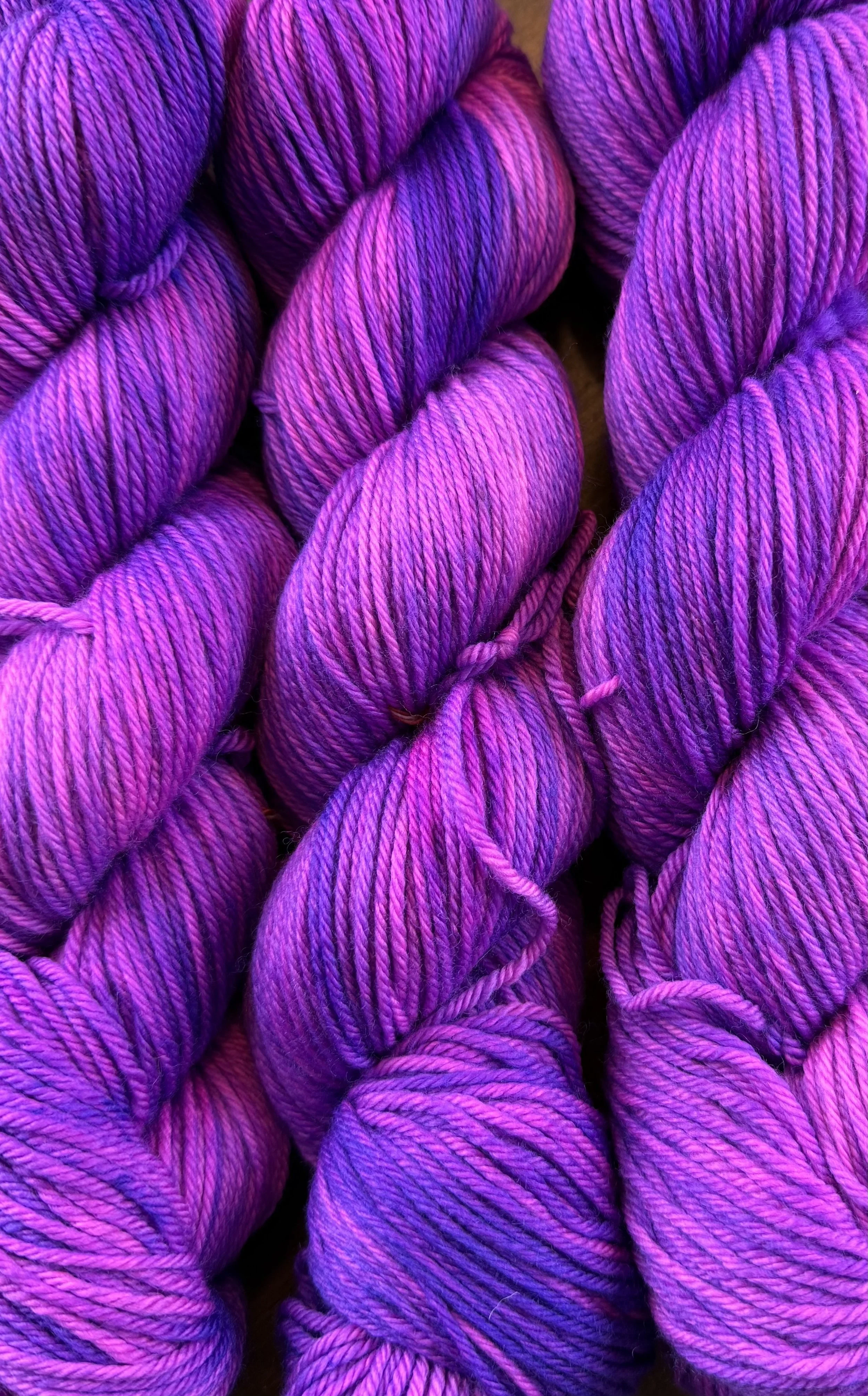 Close-up of multiple skeins of purple and pink variegated yarn.