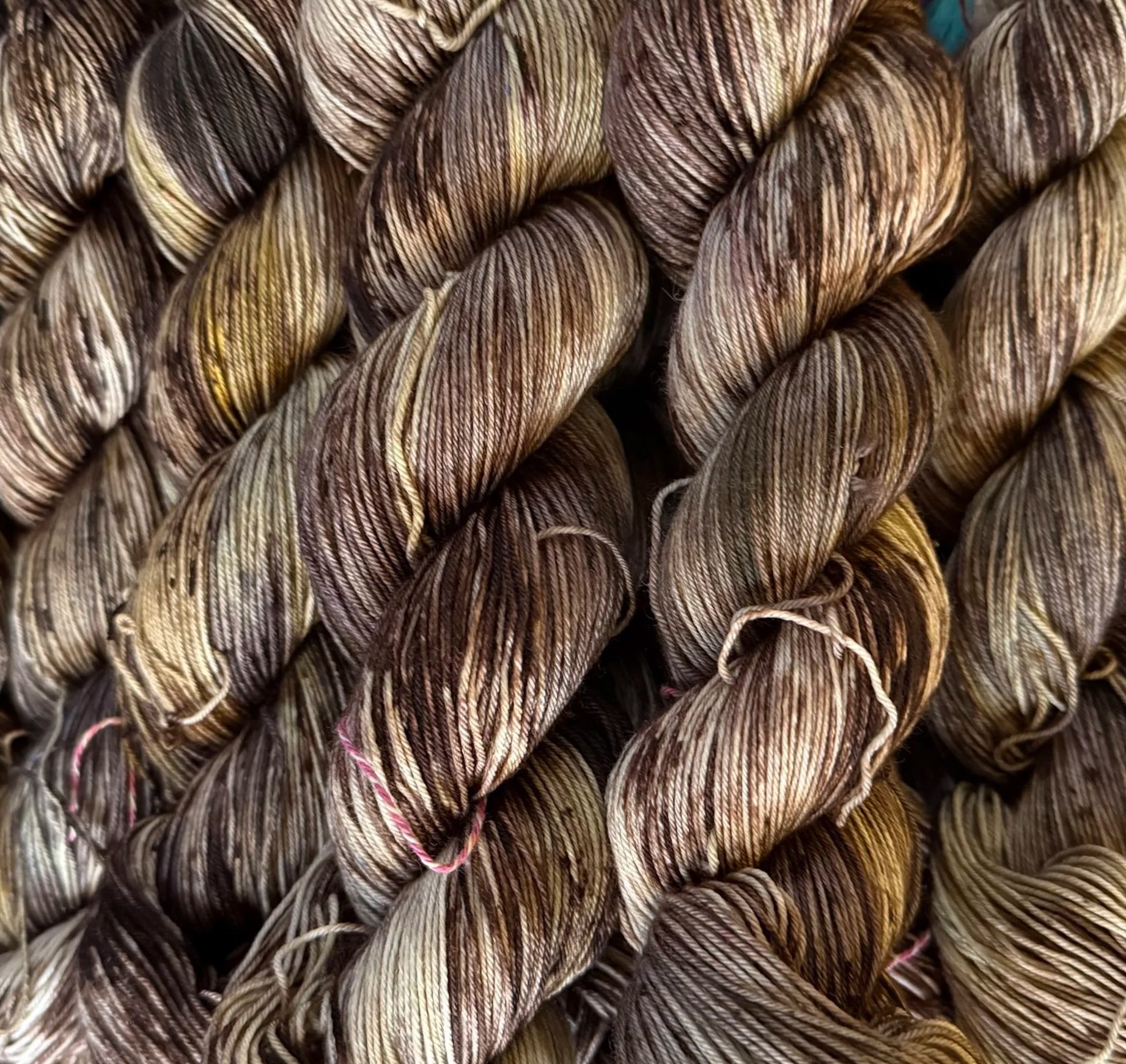 Close-up of multiple skeins of brown, beige, and black variegated yarn arranged in a parallel manner.