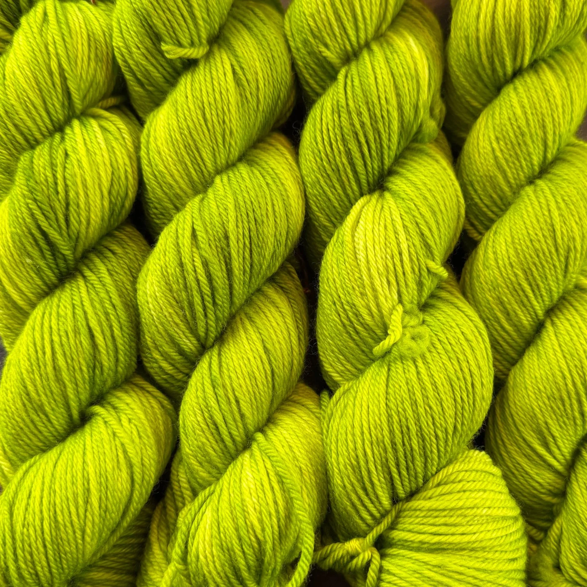 Multiple bright yellow-green skeins of yarn tightly twisted together.