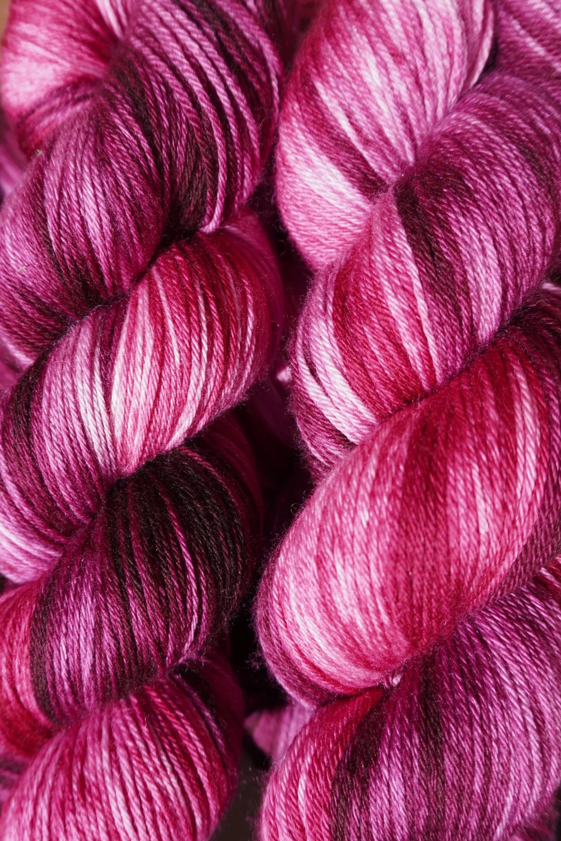 Close-up of skeins of pink and purple variegated yarn with a shiny texture.