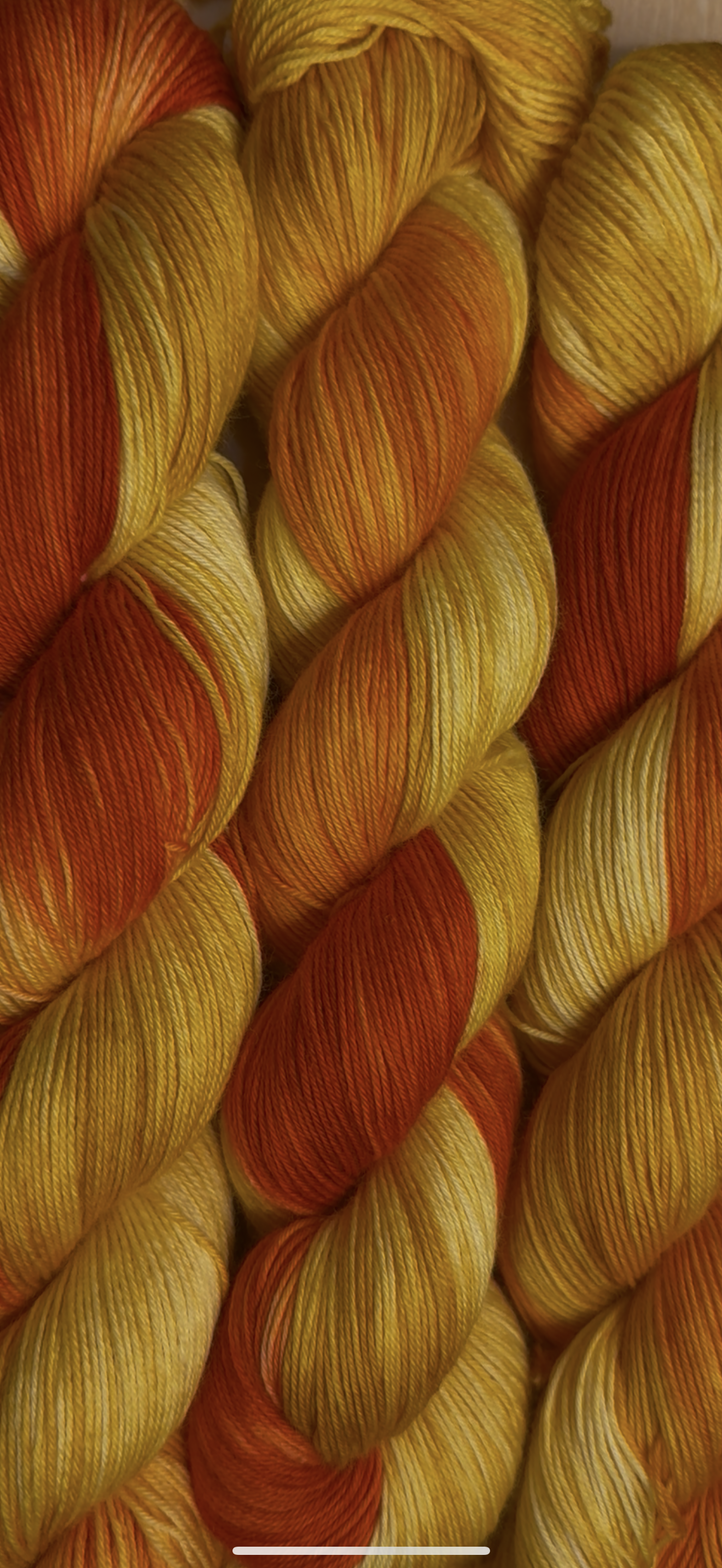 Close-up of multiple skeins of yellow, orange, and cream-colored yarn twisted together.