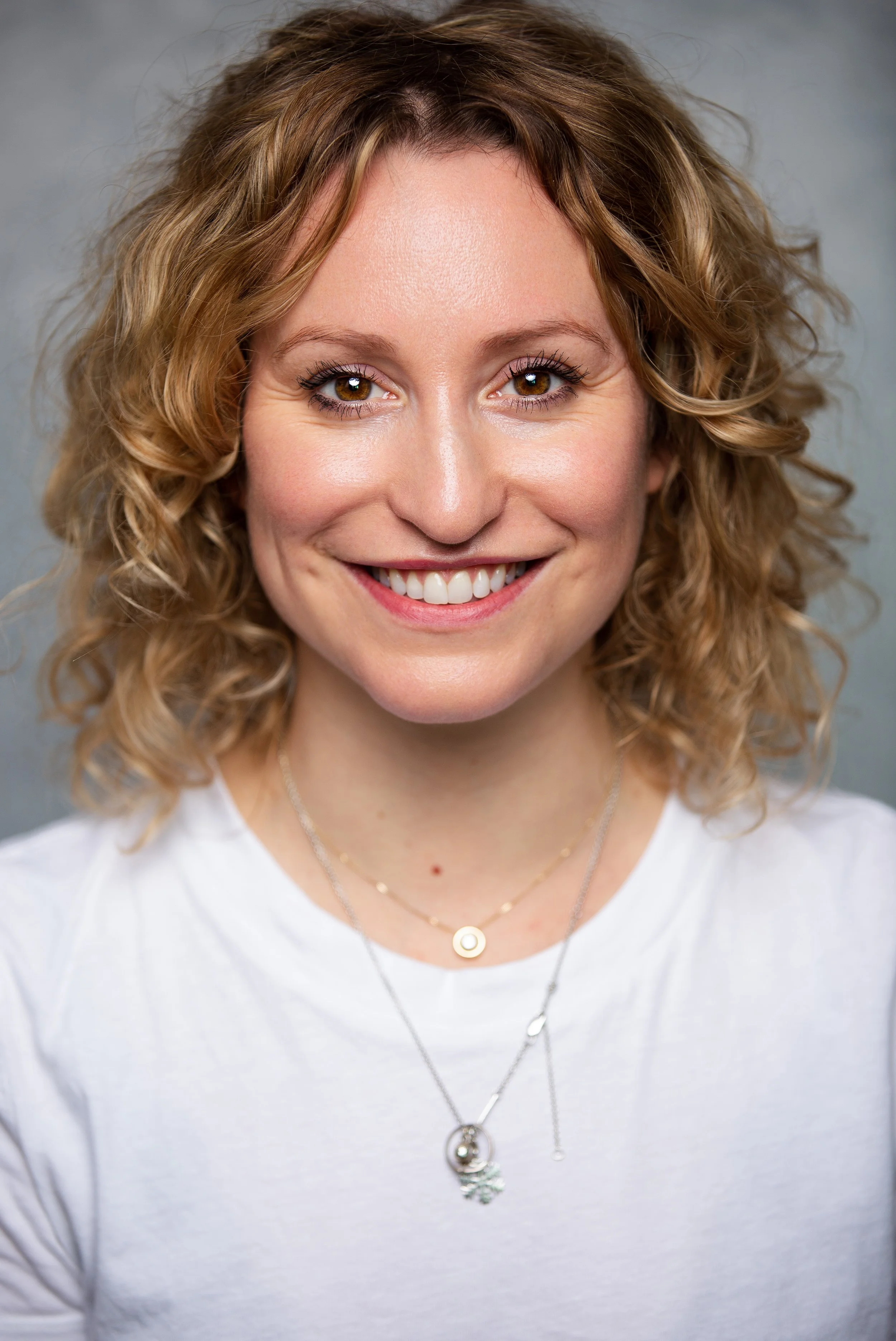 Photo of Carrie Taylor-Johnson wearing a white t-shirt and silver necklace.