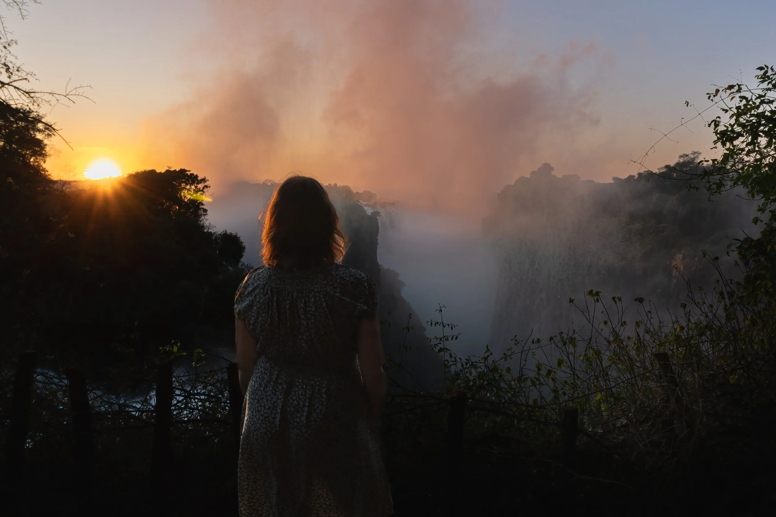 Sunrise over Victoria Falls in Zimbabwe, showcasing misty waterfalls and vibrant morning sky