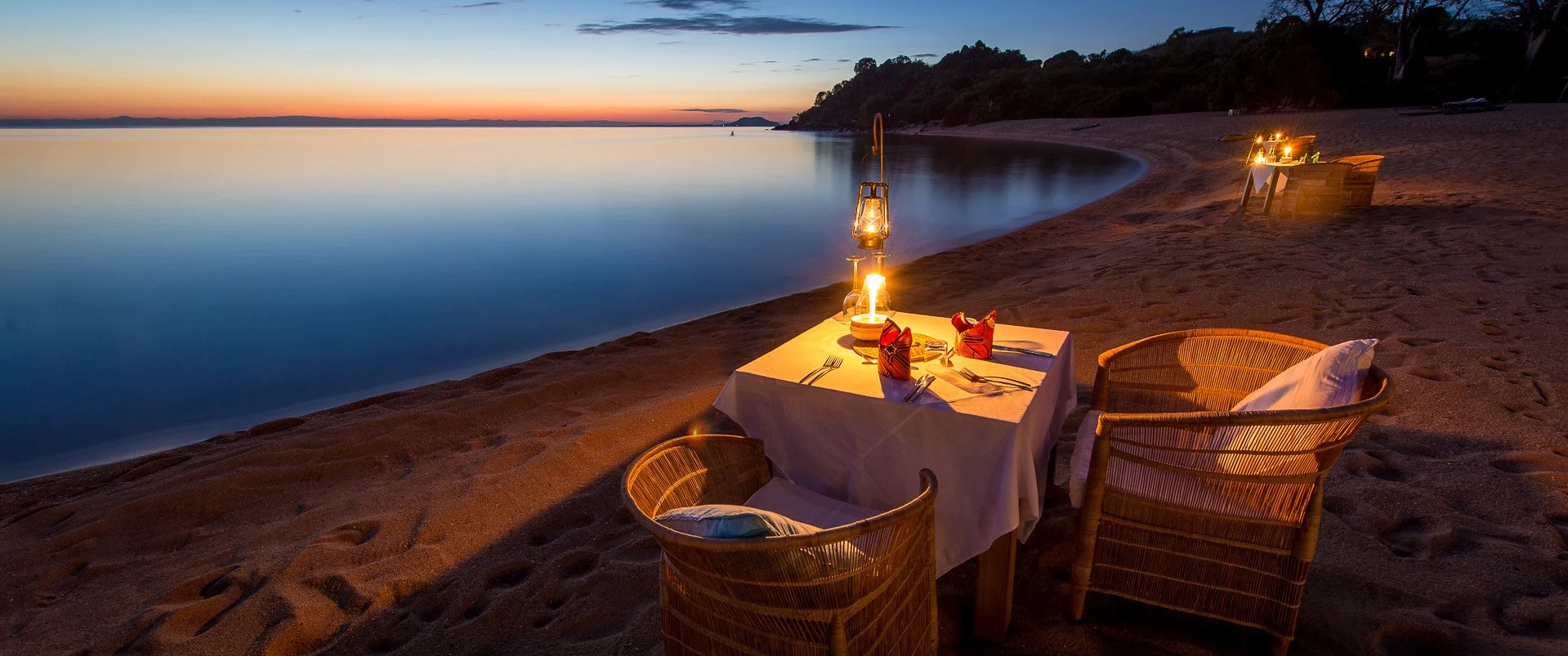 Romantic dining table on a beach at sunset in Malawi during African safari holiday
