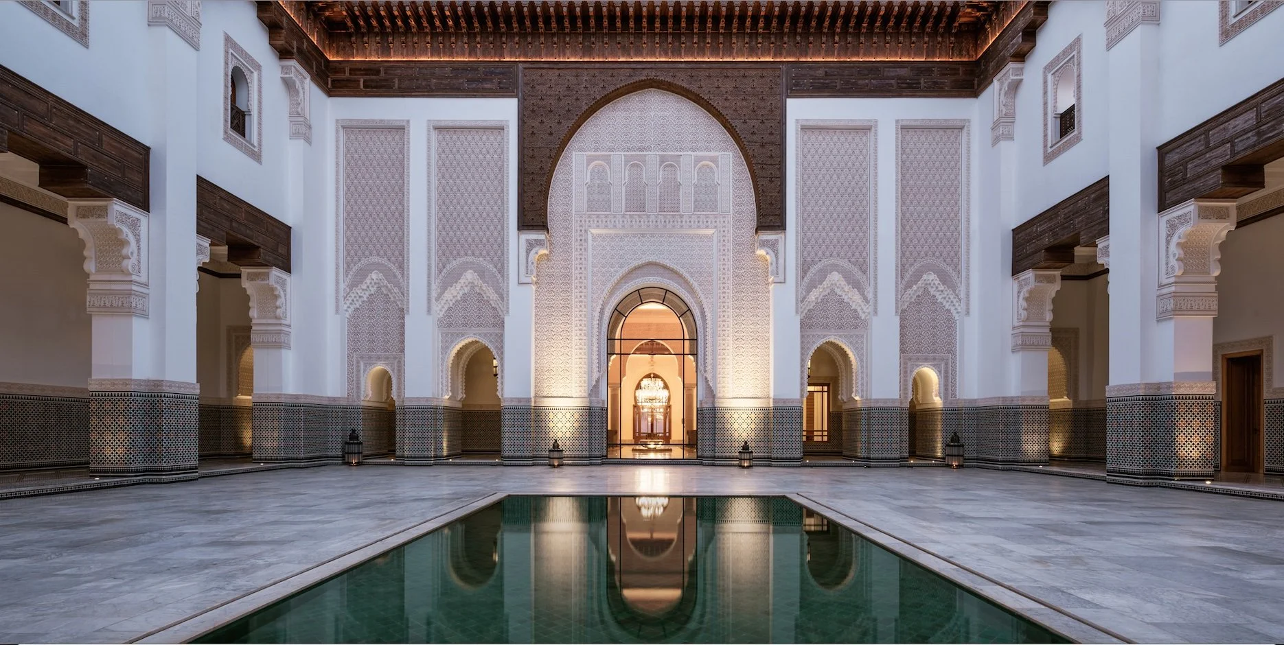 Interior view of a grand Ottoman-style palace with intricate arches, patterned walls, and a central reflective pool.