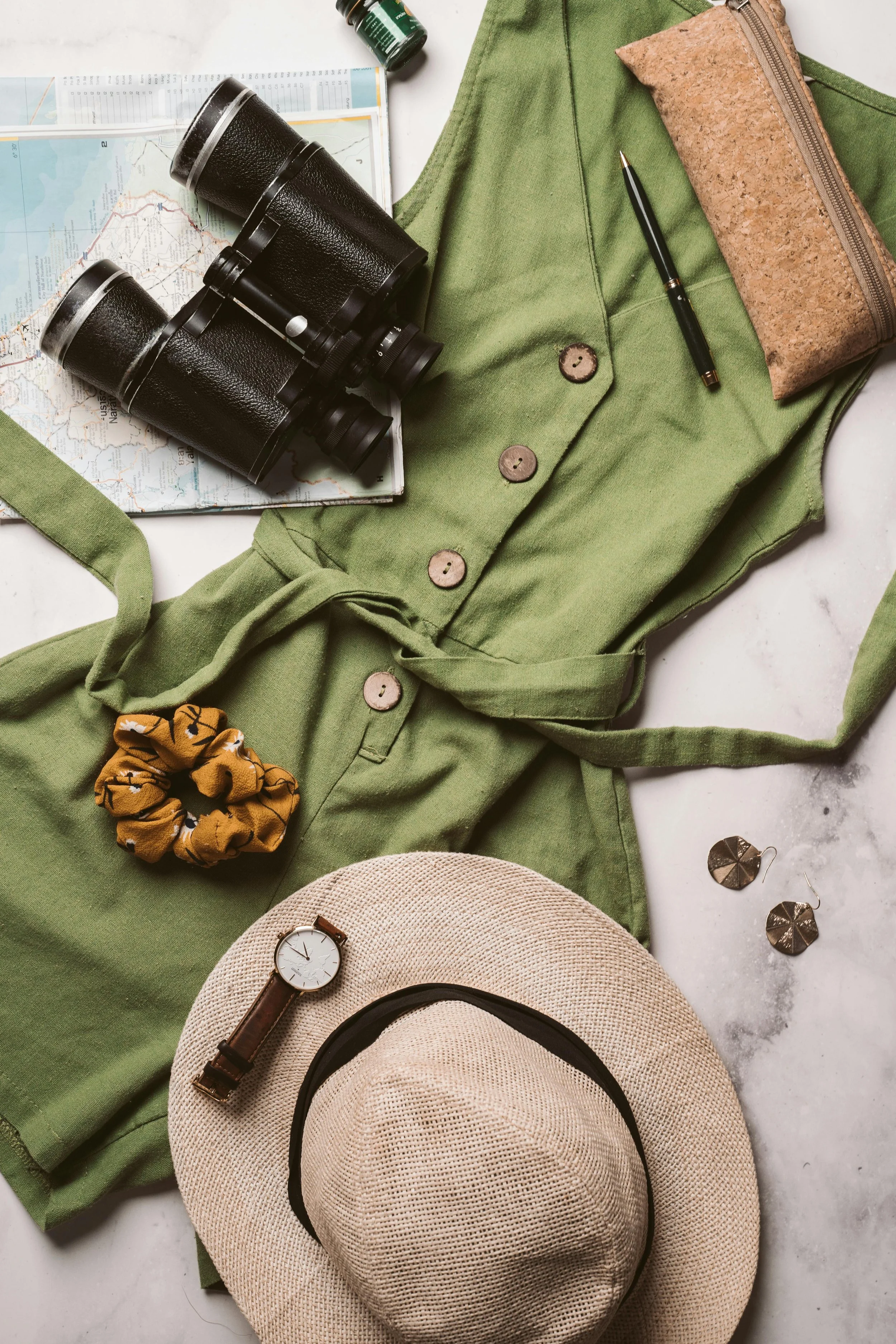 Safari packing essentials including neutral clothing, hat, binoculars, camera, and travel documents laid out before trip
