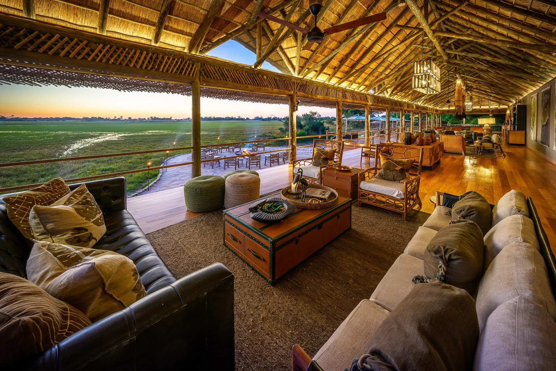 Open-air thatched lounge and firepit area in a luxury African safari camp