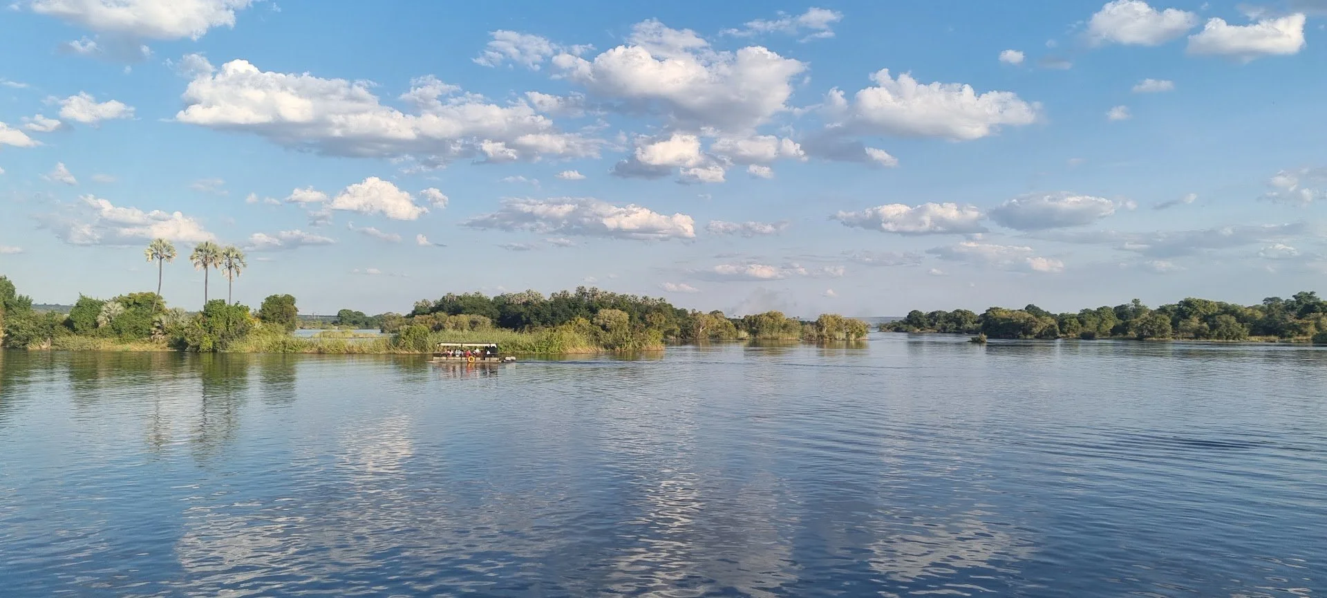Luxury river cruise on the Zambezi River with travellers observing wildlife along the banks on a luxury safari