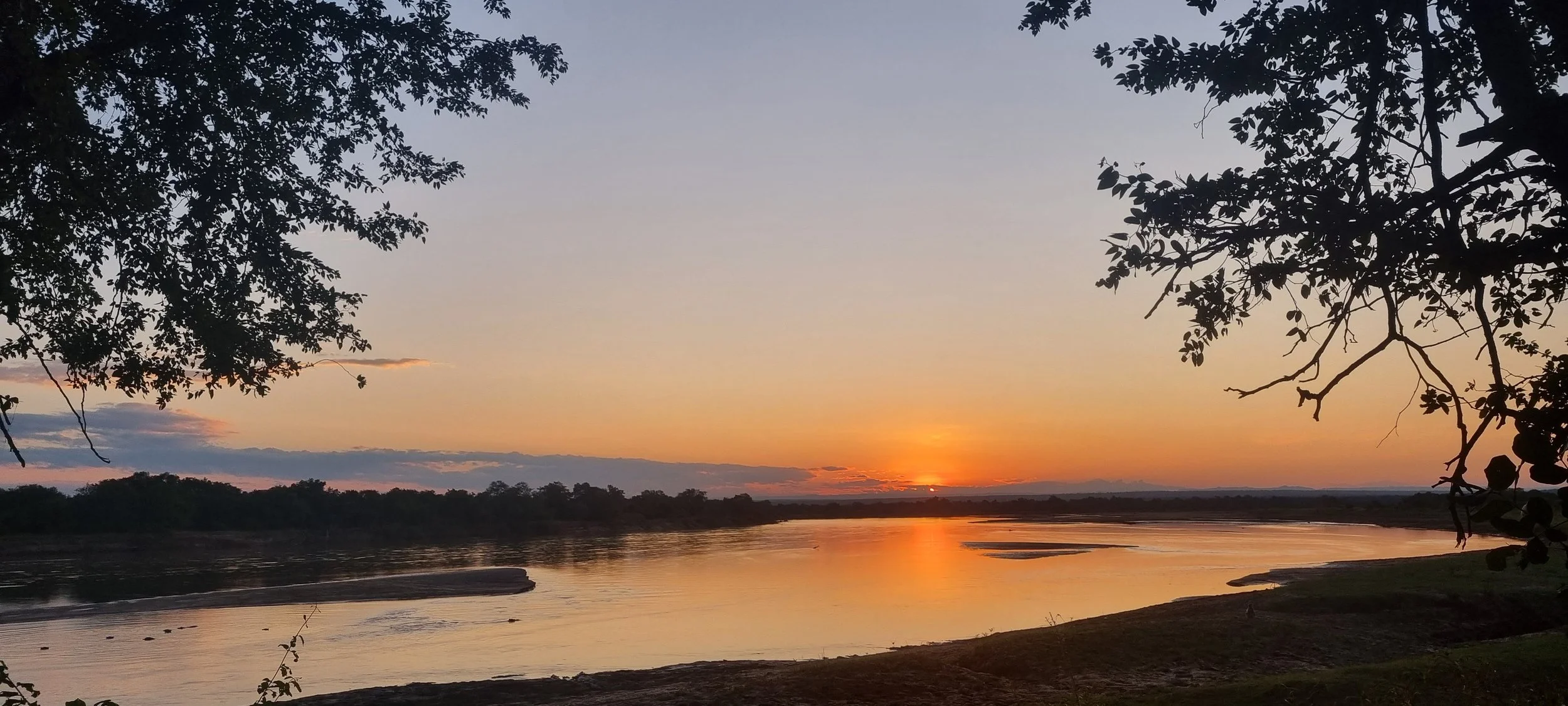 Sunset over the Luangwa River in Zambia with vibrant sky and calm waters