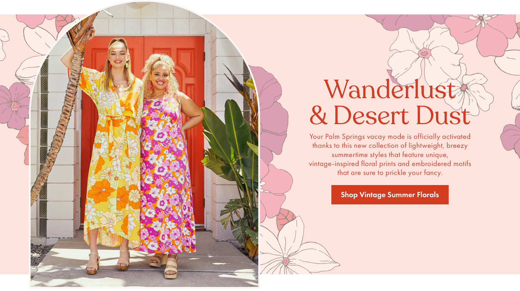 Two women in colorful floral dresses standing outside a house with a red door, smiling and posing for a photo. One woman has blonde curly hair and the other has blonde straight hair. There are green plants and a tree branch nearby, with a pink floral