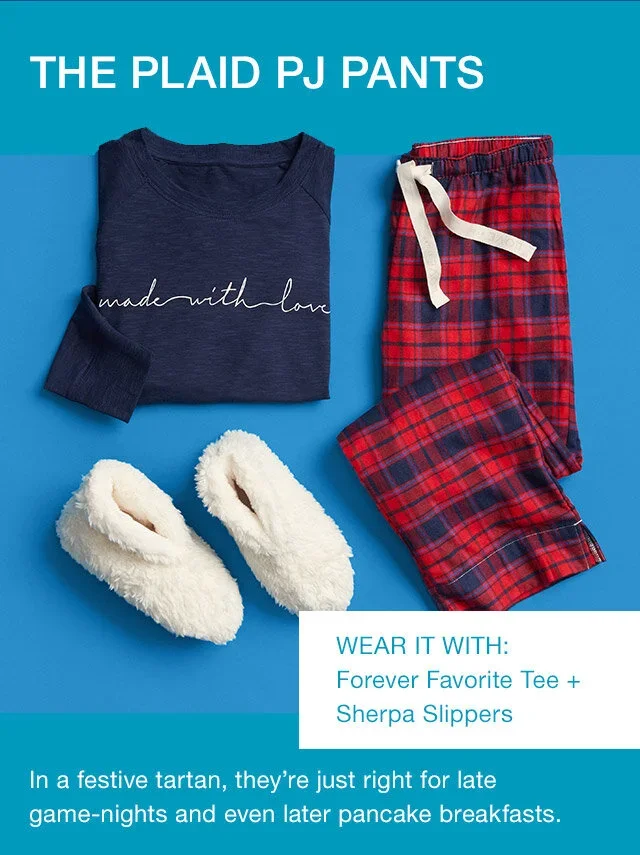 A navy blue 'made with love' T-shirt, red plaid pajama pants, and fluffy white slippers displayed on a blue background with text promoting these pajamas for late game nights and pancake breakfasts.