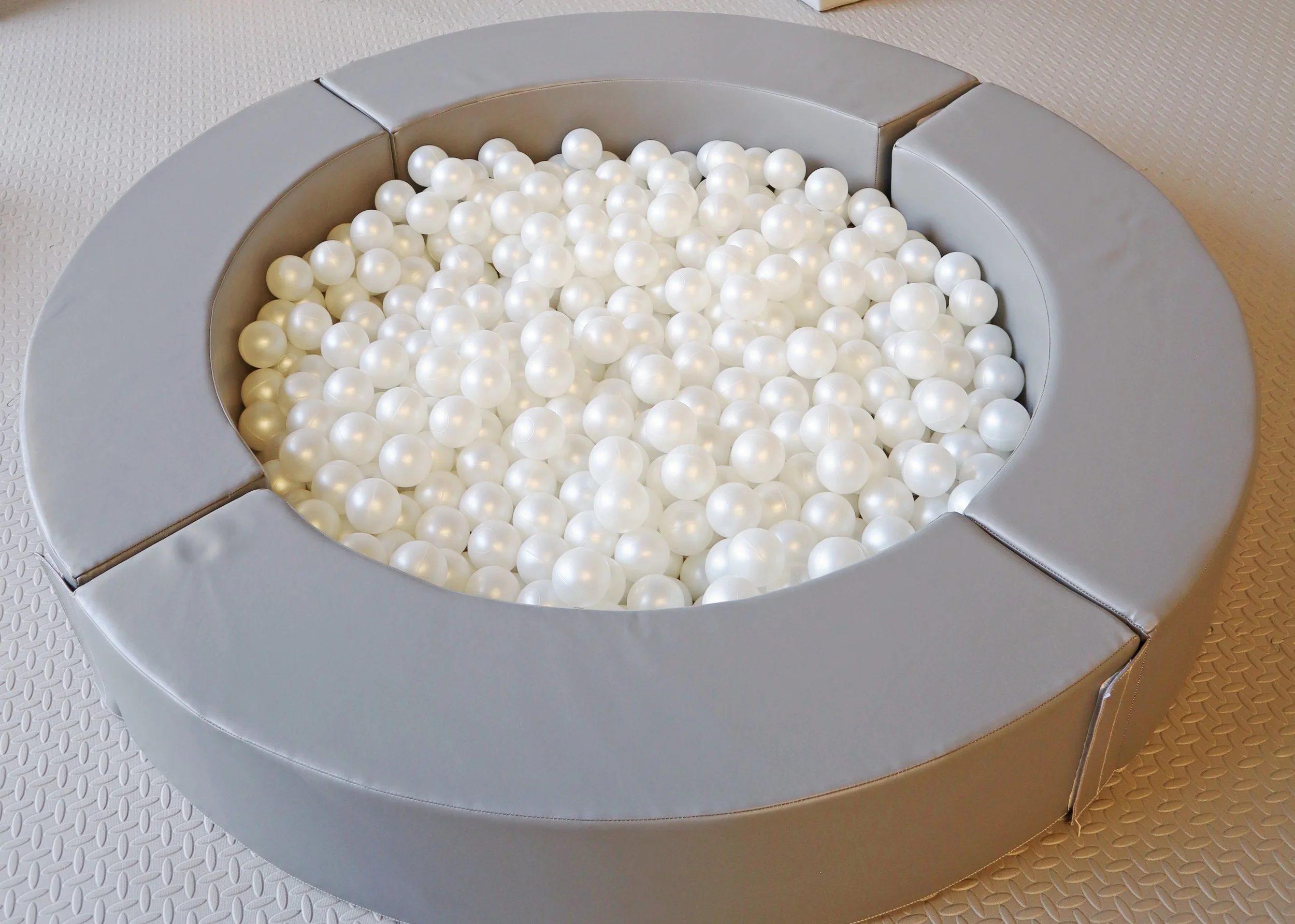 Circular padded seating area filled with white plastic balls.