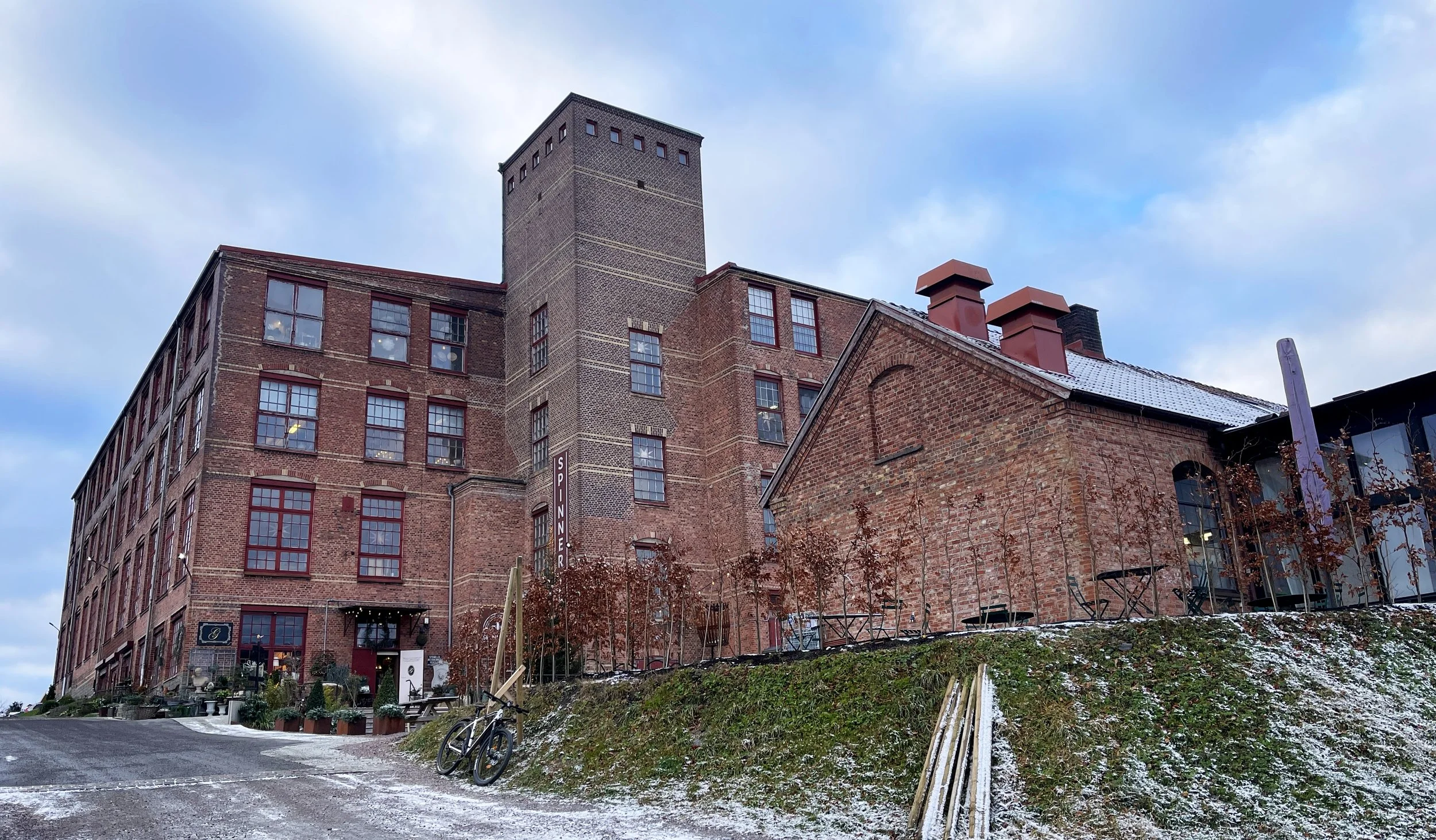 Spinneriet in Lindome. A large brick industrial building with multiple windows, a tower and filled with cosy shops and fika. Here you will find Design & CO.