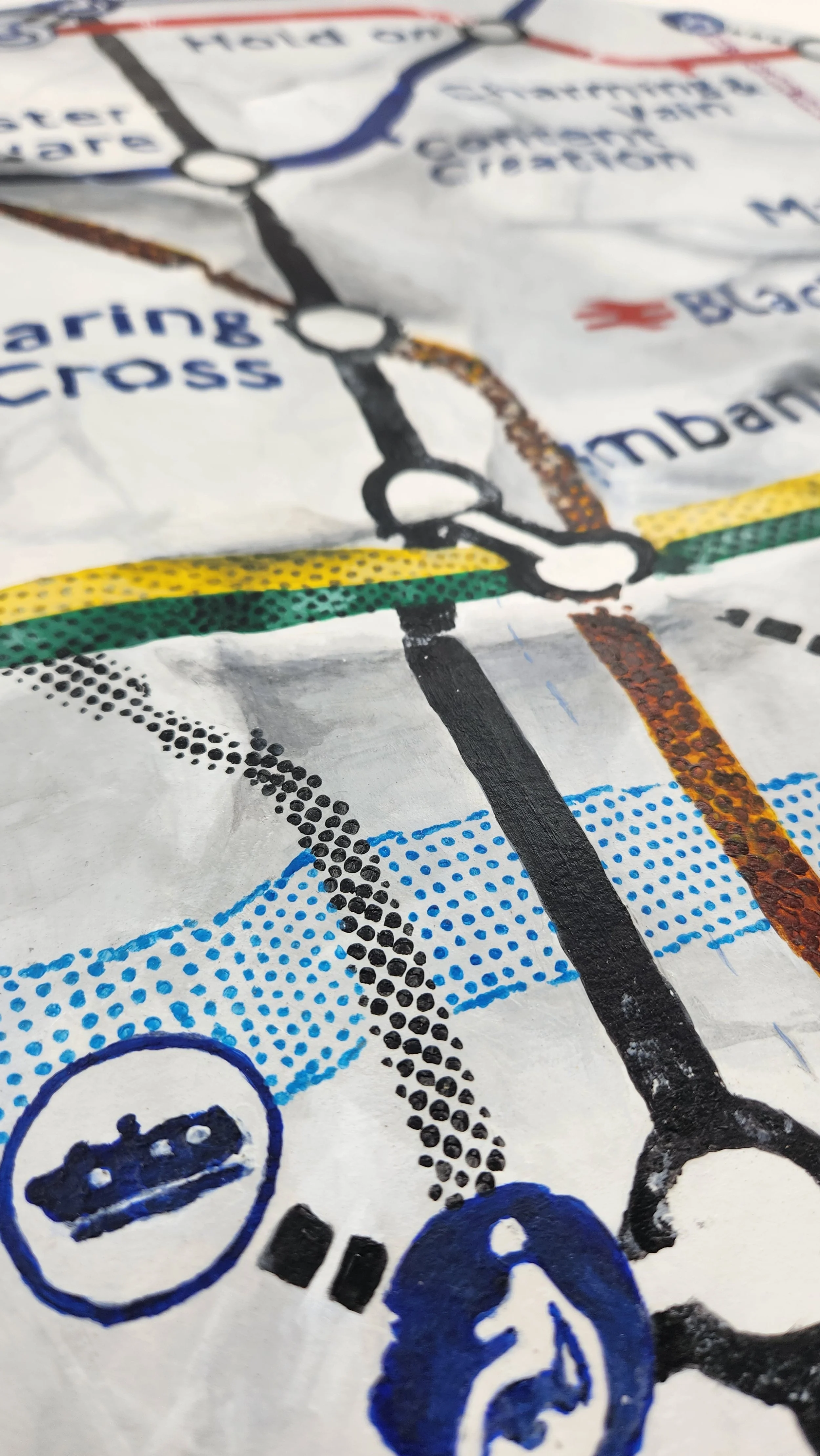 Close-up of a hand-drawn map of a subway or train line with colored lines and station names, showing symbols representing different transportation modes.