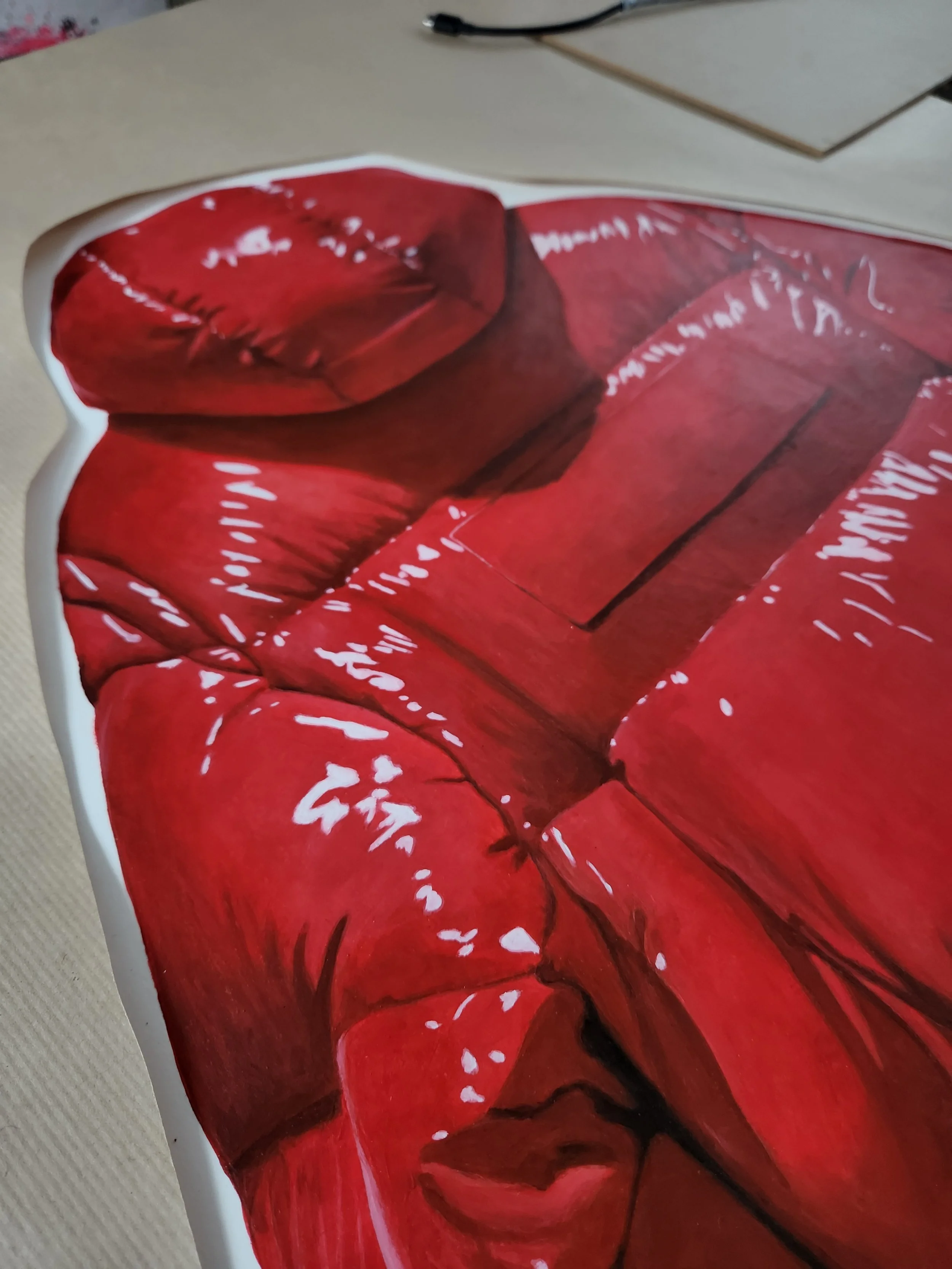 Close-up of a table with a large red painting of a sofa with white handwritten text and markings.