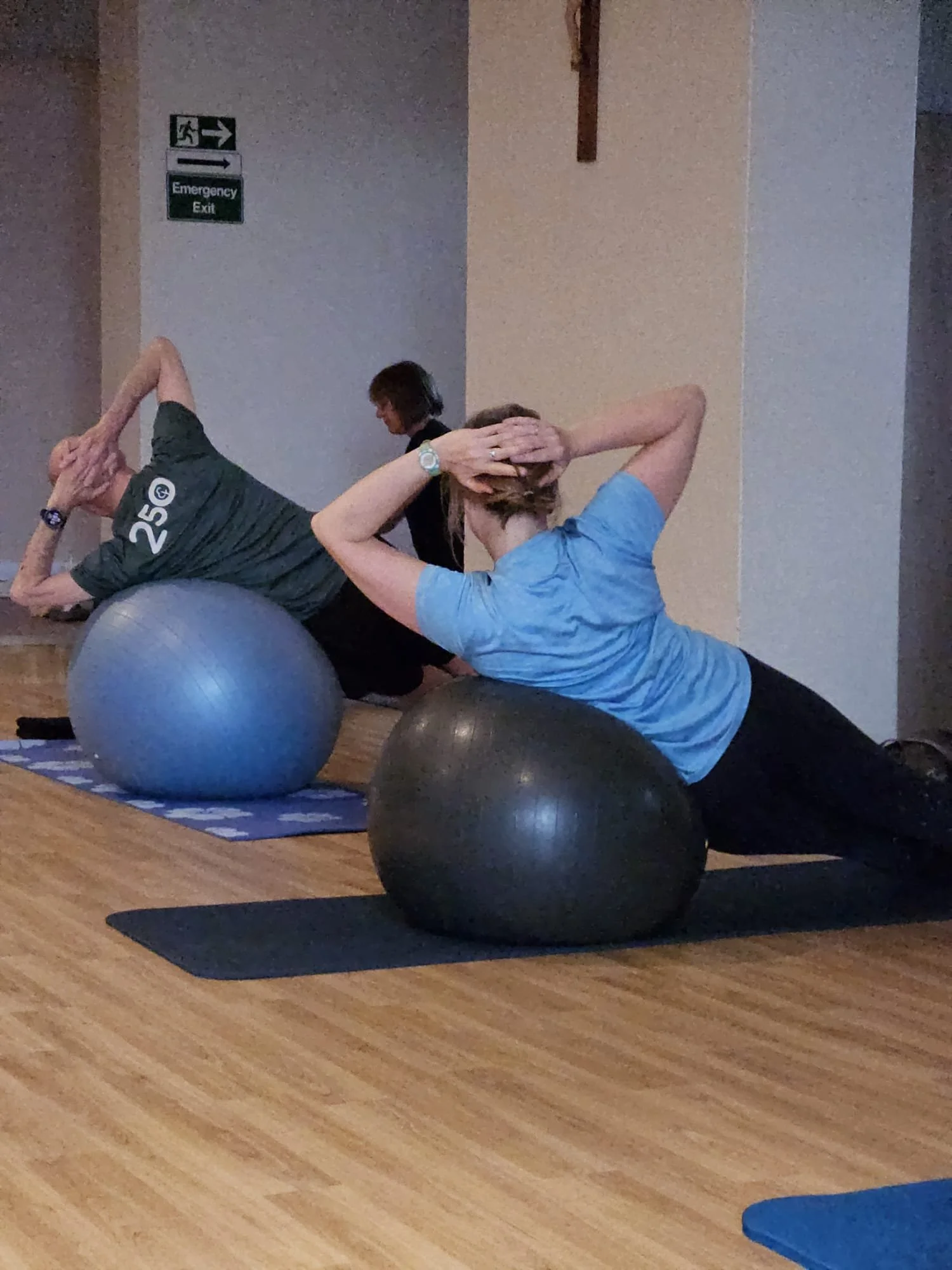Two people doing abdominal exercises on exercise balls during a fitness class.
