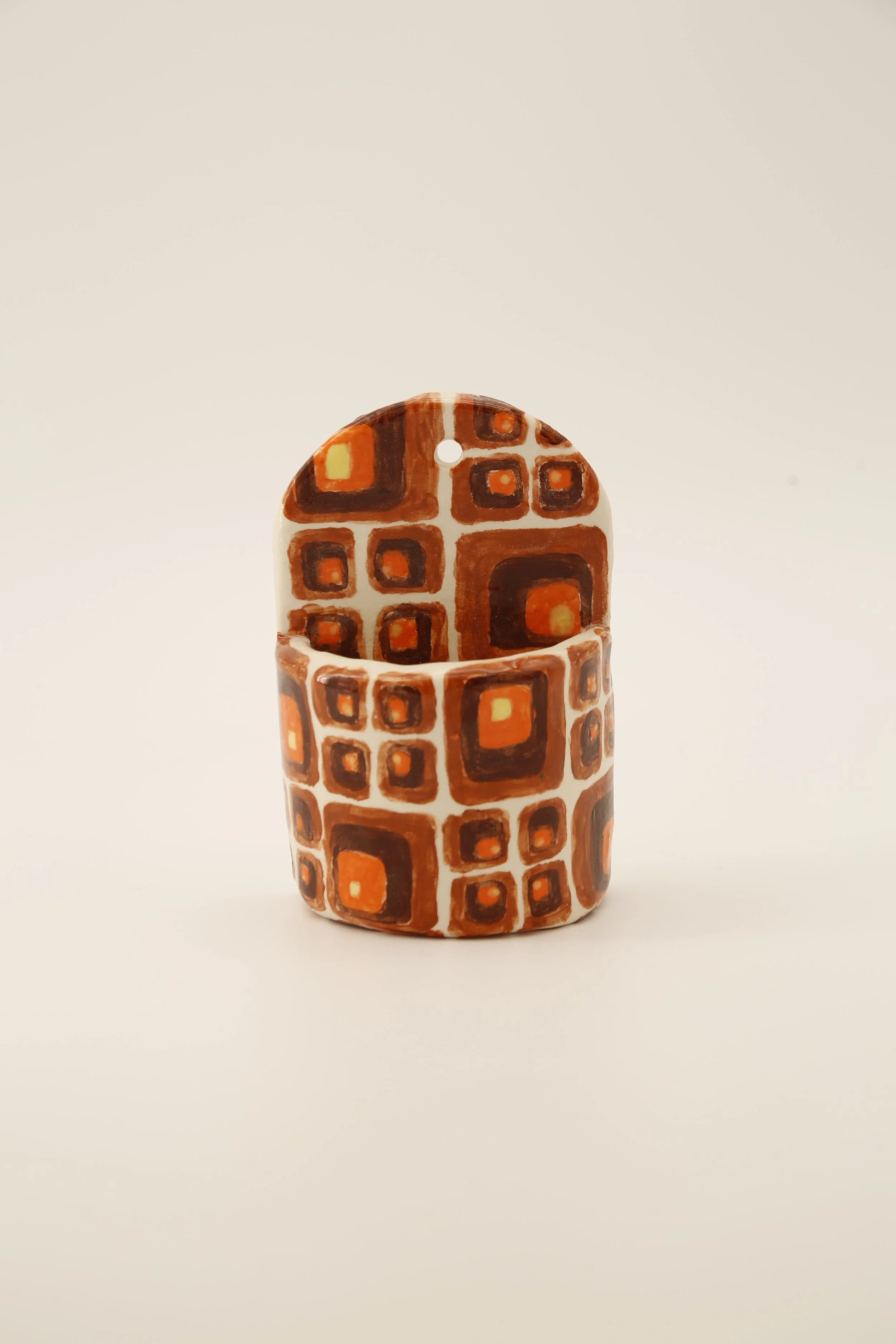 Ceramic wall planter with 60s/70s decade orange and brown square pattern on a plain white background.