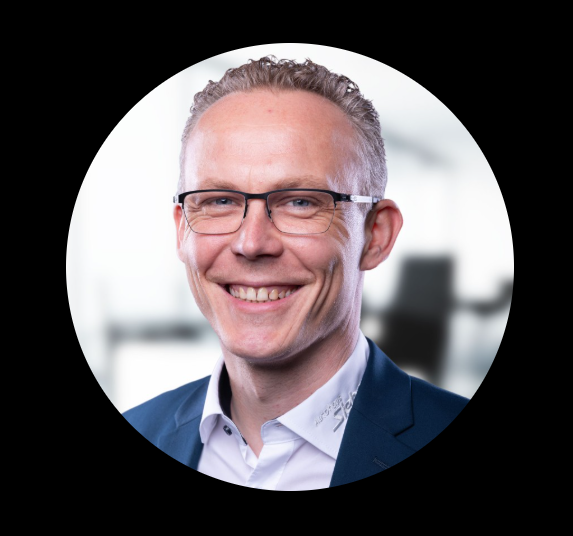 Porträt eines lächelnden Mannes mit Brille in Business-Kleidung, im Bürohintergrund
