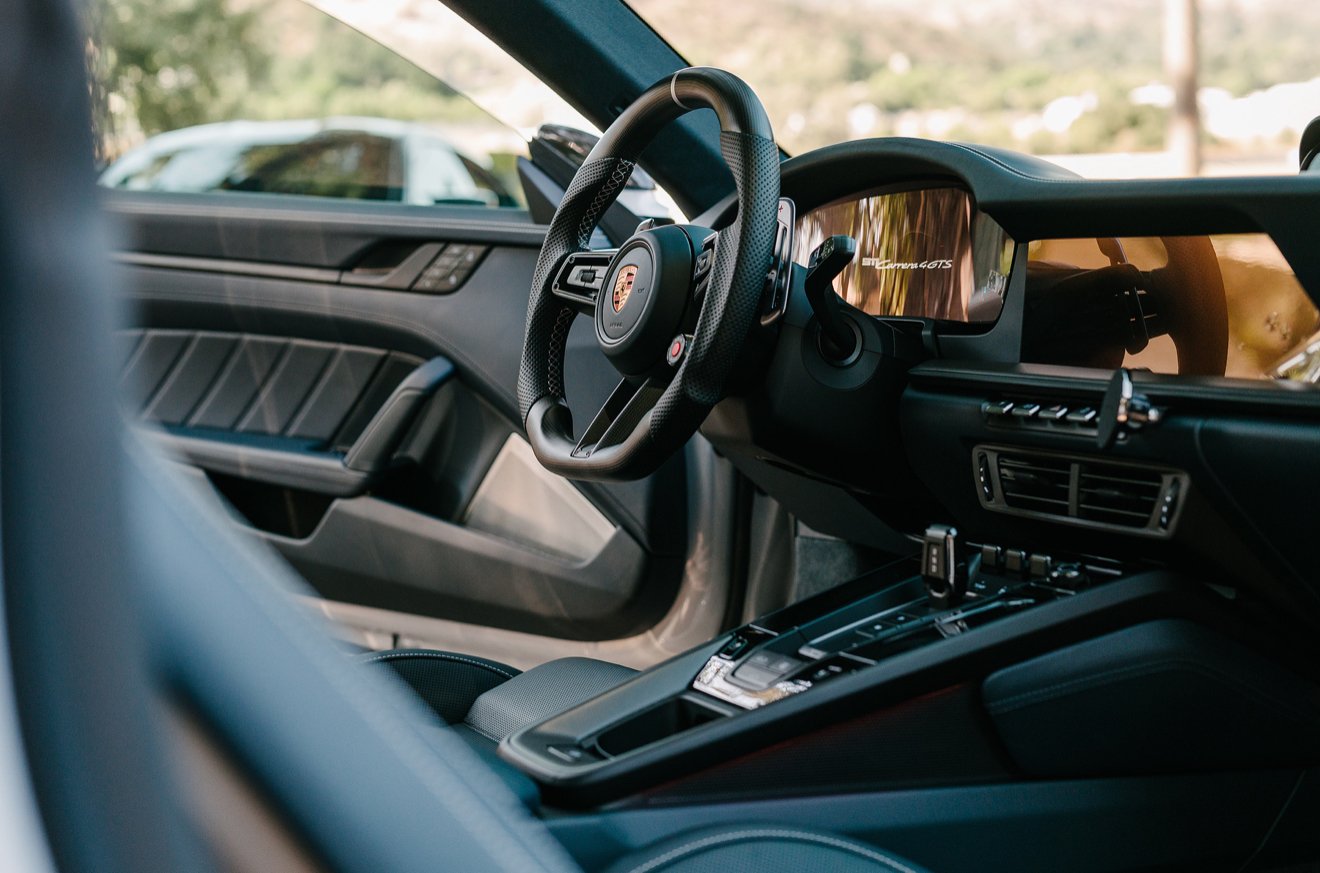 Interior of a sports car with a Porsche steering wheel, digital dashboard, and center console.