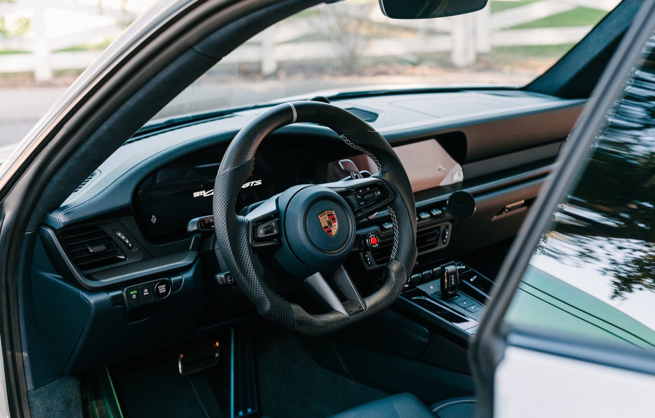 Interior of a Porsche sports car showing the steering wheel and dashboard.