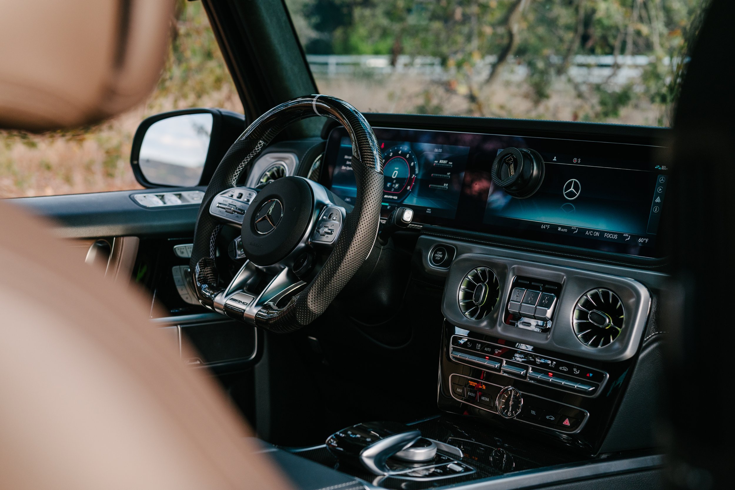 Interior of a luxury Mercedes-Benz vehicle, showing a digital dashboard, steering wheel, and central console with climate controls and multimedia system.