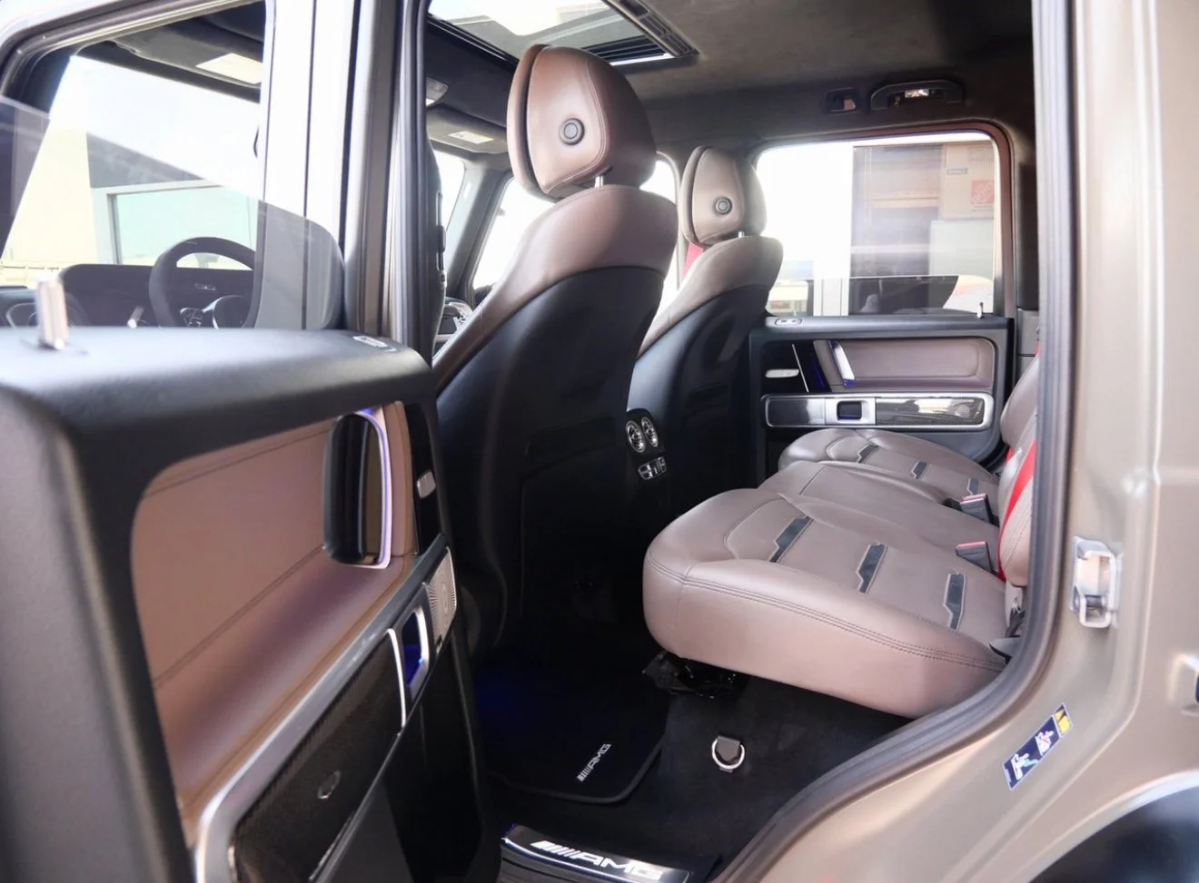 Interior of a luxury vehicle showing beige seats, rear air vents, and a sunroof with sunlight coming through.
