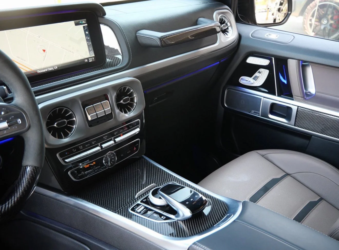 Interior of a luxury car showing the dashboard, climate controls, central console with a control knob, and passenger seat.