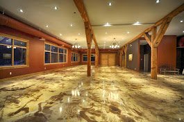 Empty room with wooden beams and polished custom epoxy floor, illuminated by ceiling lights custom made by Rooks Construction and Concrete.