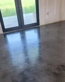 Empty room with a large glass door, custom epoxy concrete floor, and a view of a grassy outdoor area.