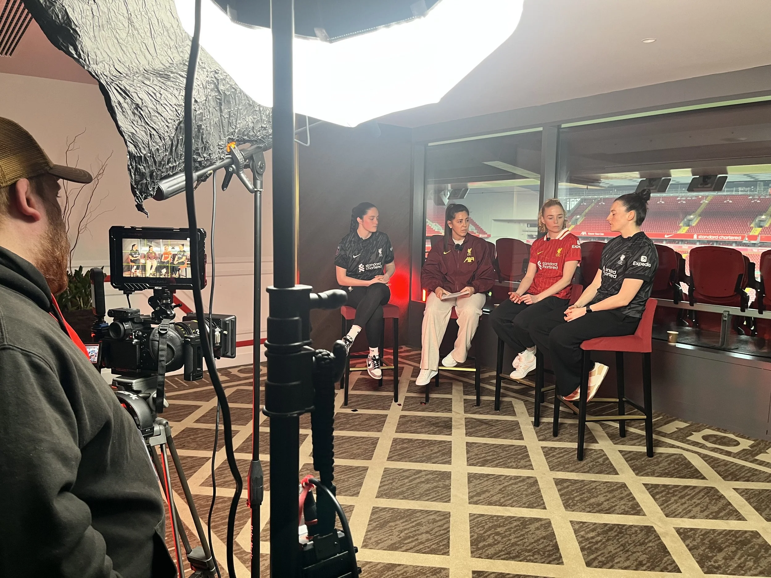 Image of 4 of the Liverpool Womens Football Team being interviewed with a camera and lighting and film crew shown in the foreground