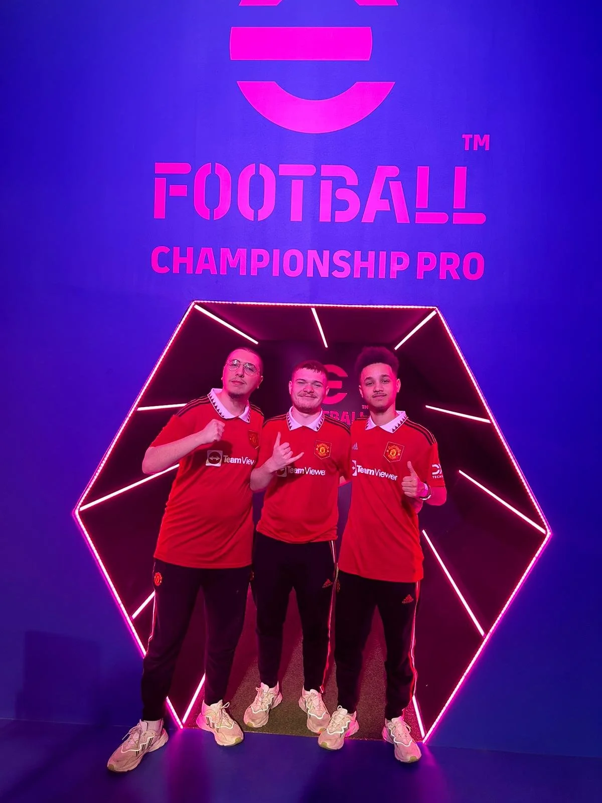 3 E footballl Champions in front of a neon backdrop