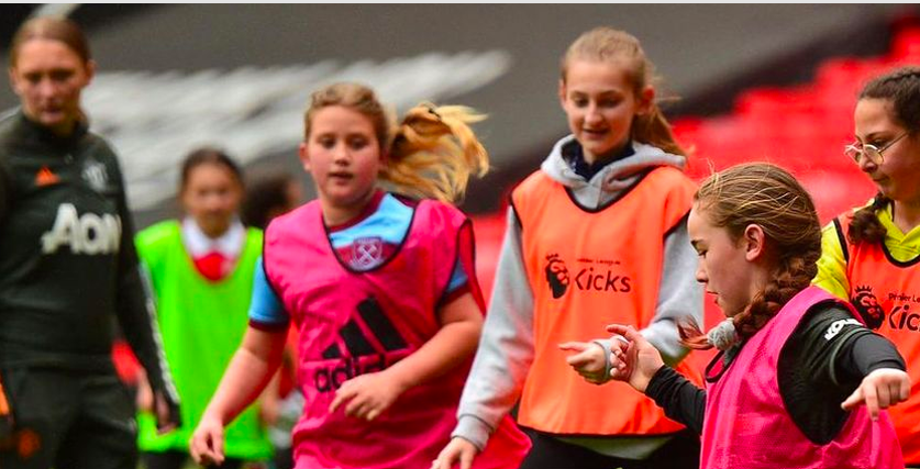 Girls play football as part of a training session wearing neon vests