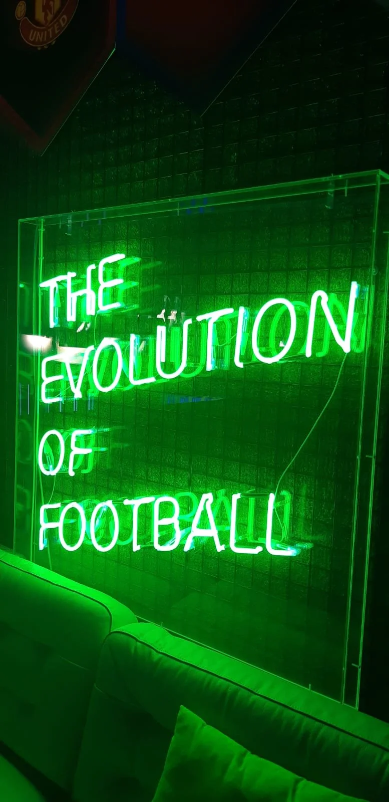 Neon Green Sign that reads: The Evolution of Football