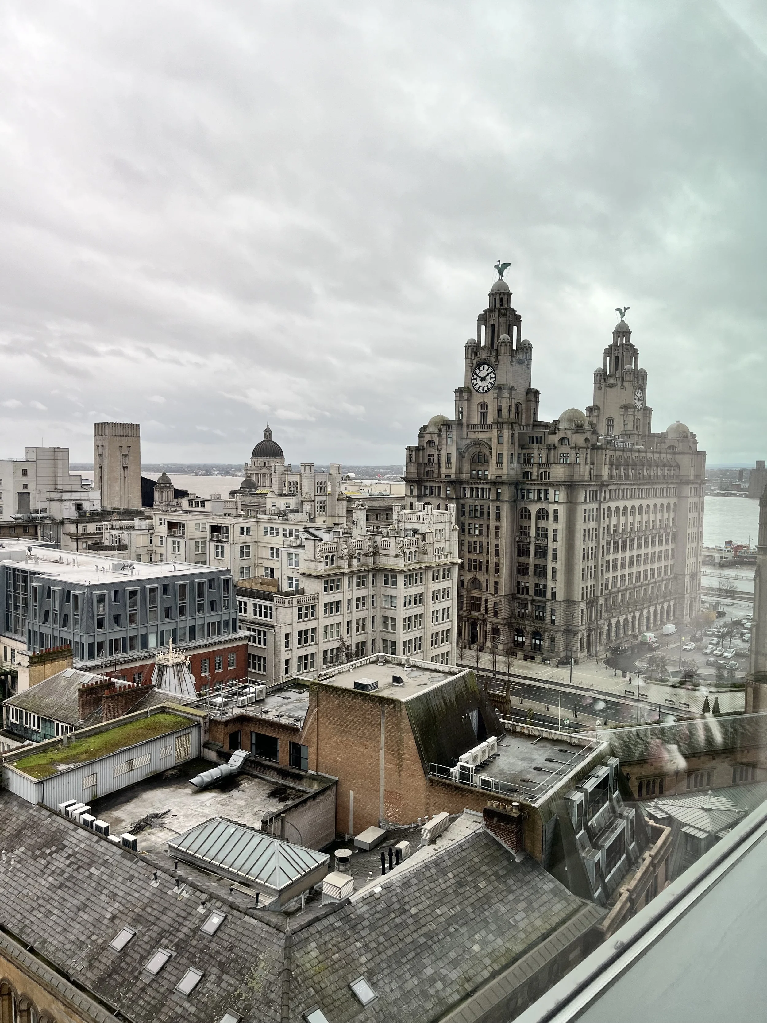 The Liver Building in Liverpool on a very grey and damp day in Liverpool. The docks are shown in the backdrop.