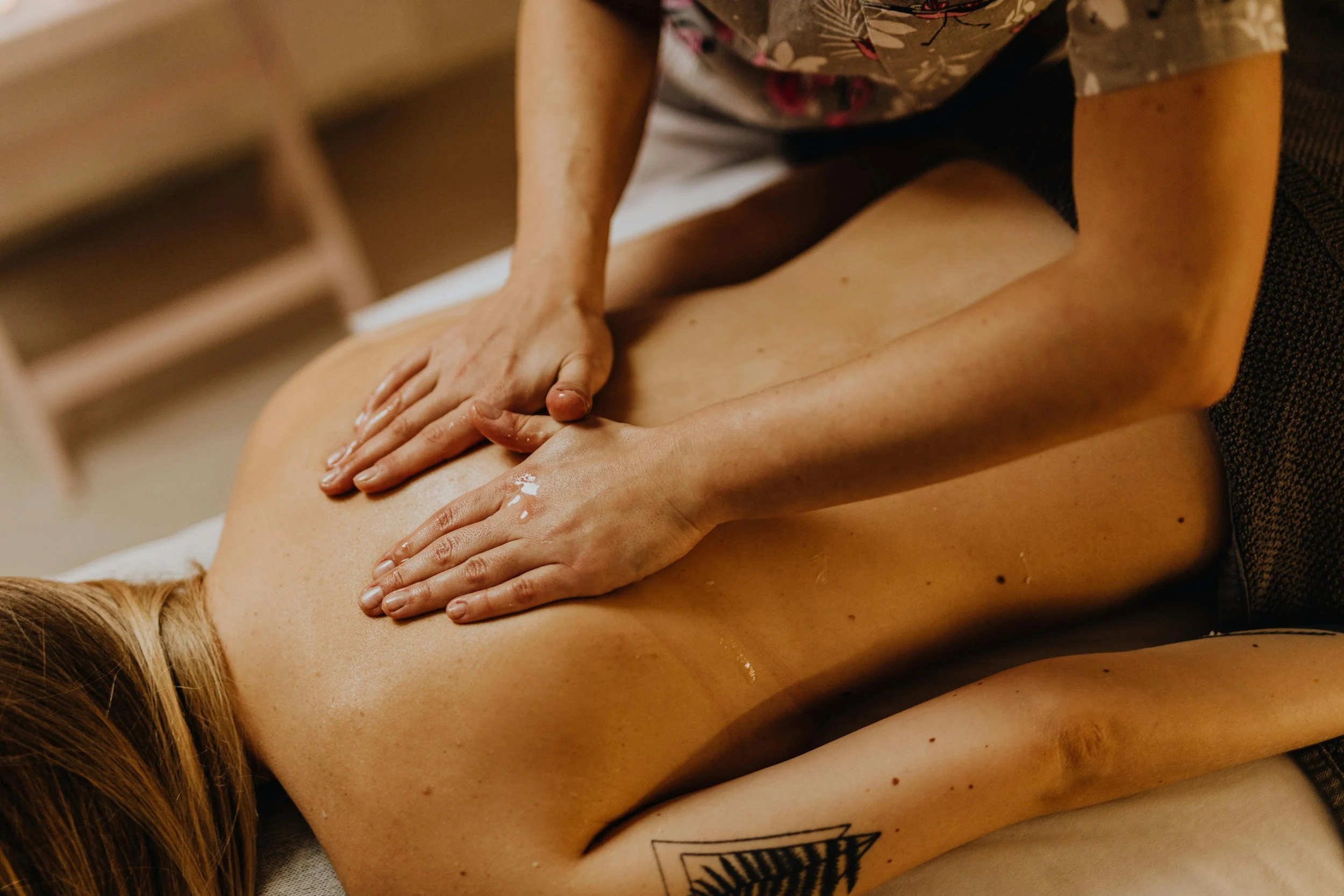 A person giving a back massage to another person lying face down on a table.