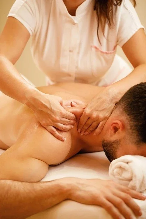 A person giving a back massage to another person lying face down on a table.