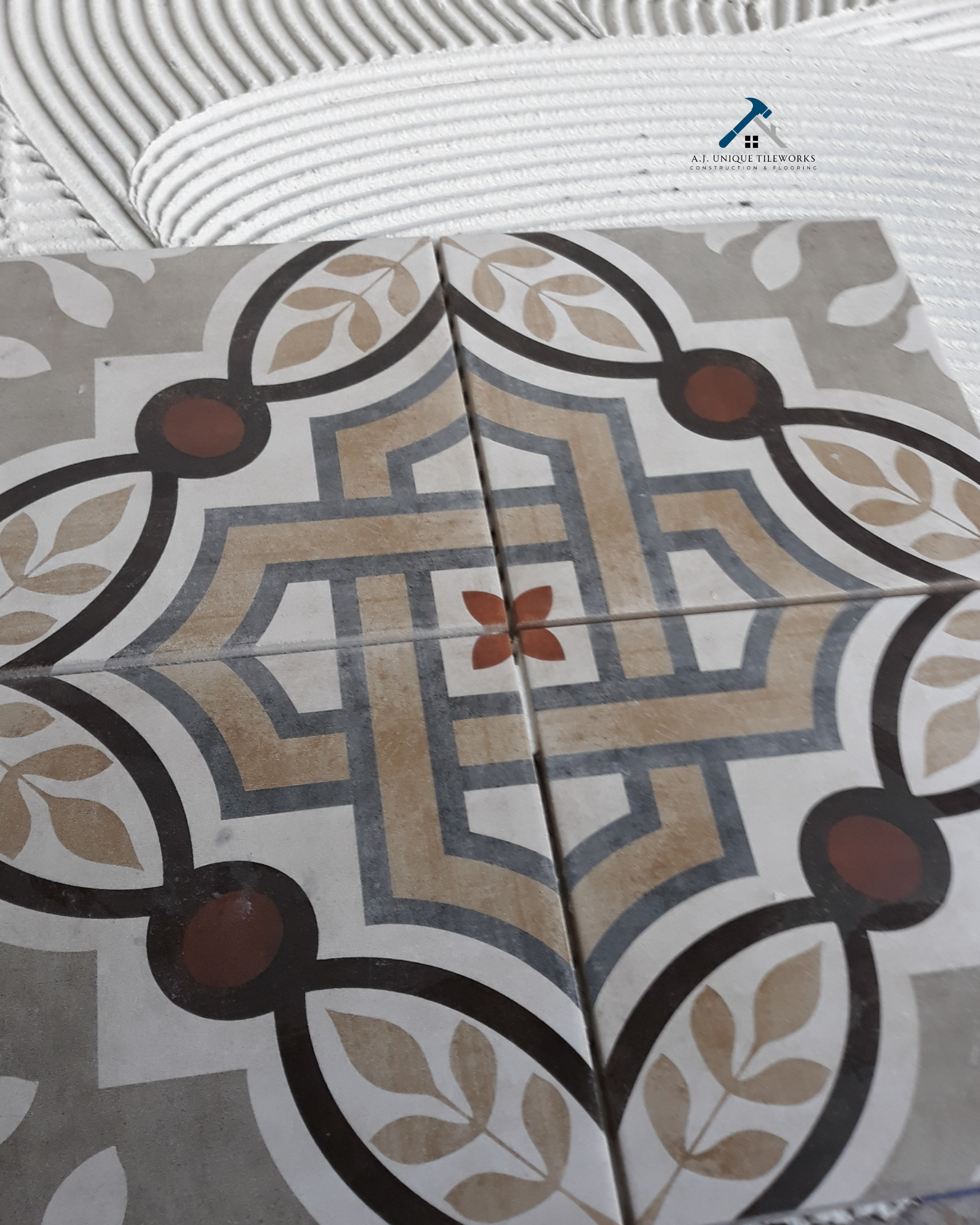 Close-up of patterned ceramic tiles with a geometric and floral design in beige, black, and red colors.