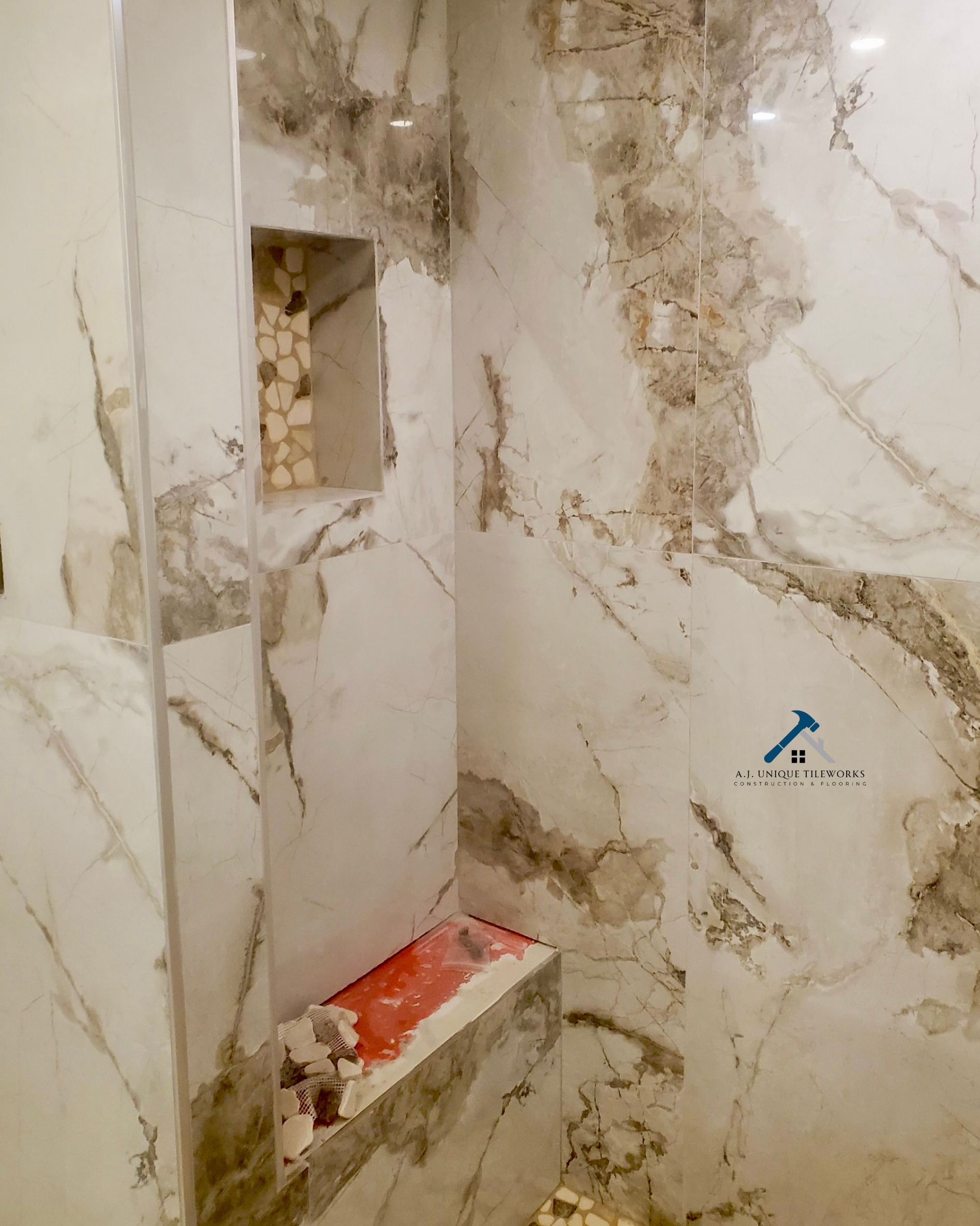 Marble tiled shower with built-in niche and a shelf with construction materials