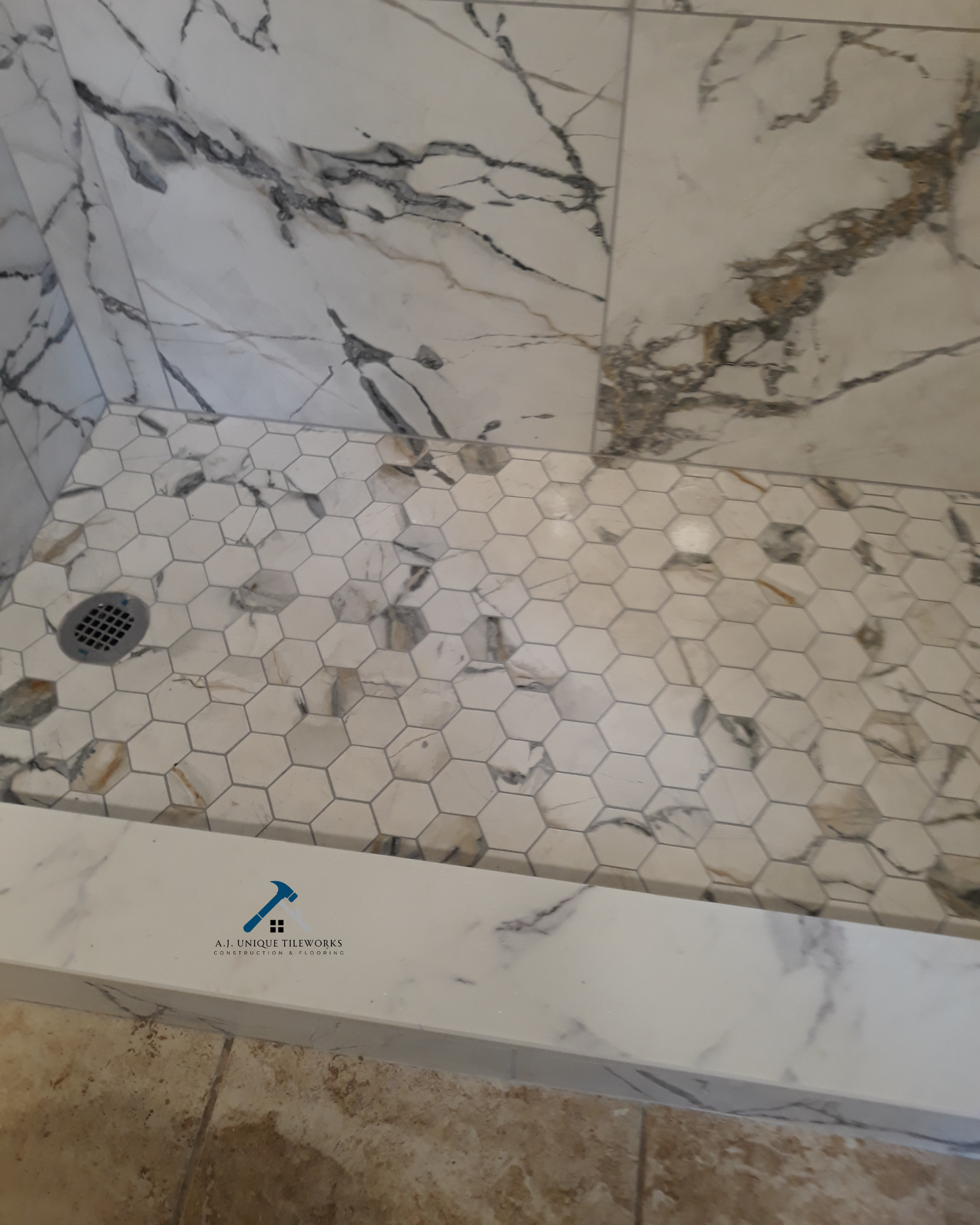 Marble shower with hexagonal tile floor and marble walls.