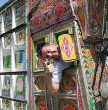 Hombre asomándose por una ventana decorada con colores y patrones tradicionales.