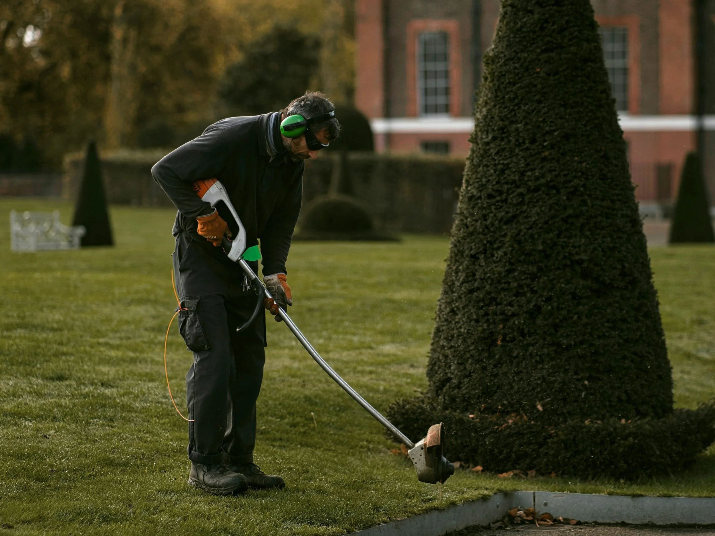 A maintenance worker trimming a lawn.