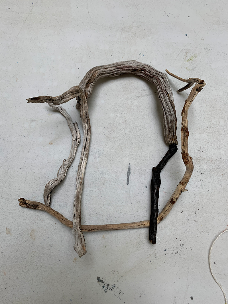 Arrangement of driftwood sticks forming an abstract face with a neutral background.