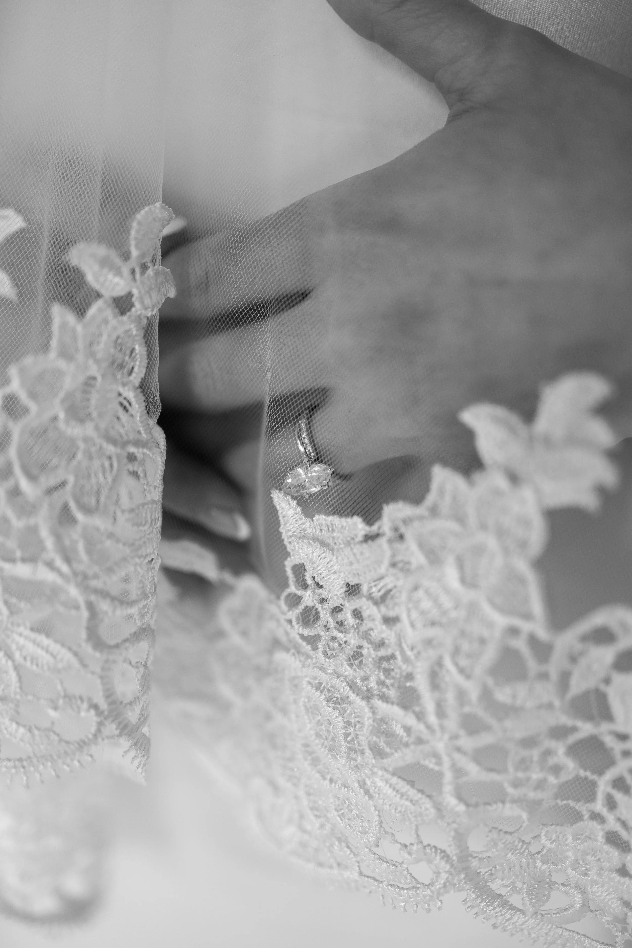 Close-up of a woman in lace bridal veil and earrings with her eyes closed, appearing to be in a moment of reflection or serenity.