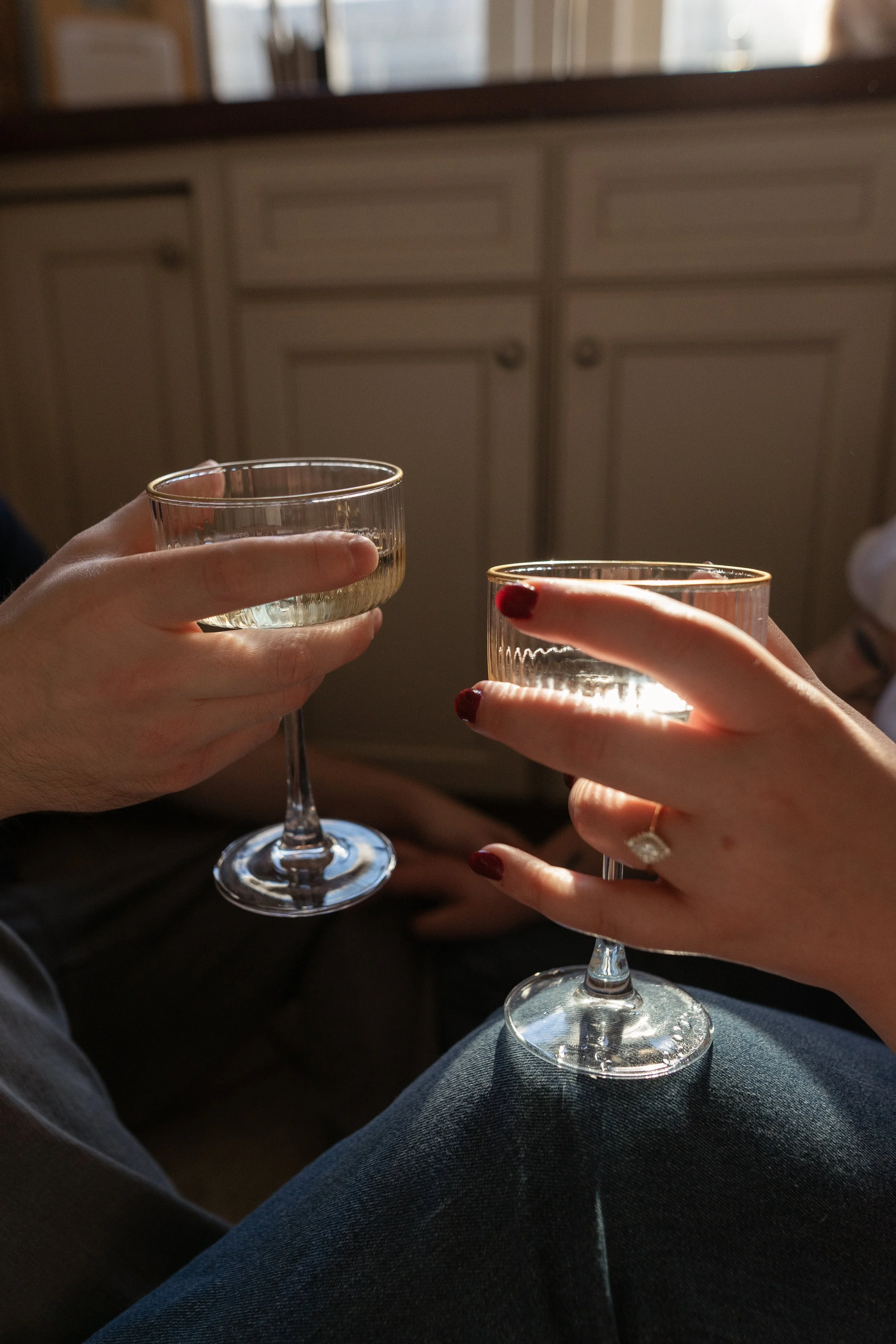 Two people clinking glasses of white wine in a cozy indoor setting.