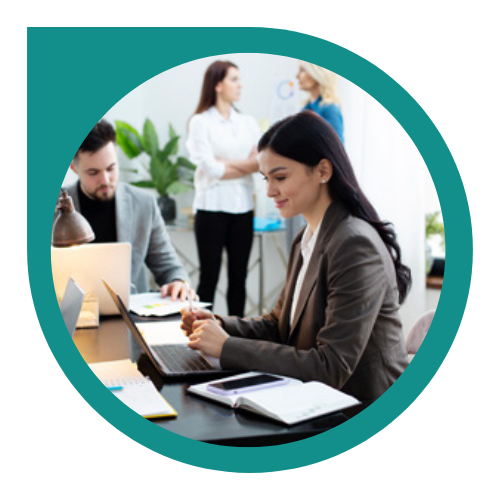 Business meeting with three professionals in an office, two women and one man, with laptops, notebooks, and a plant in the background.