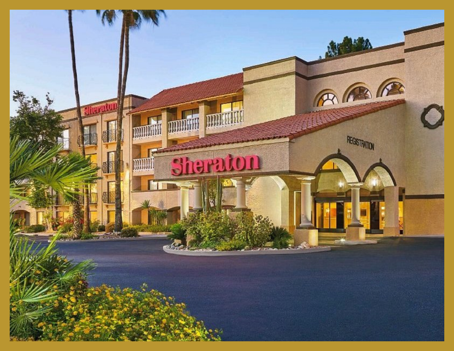 Exterior of a Sheraton hotel with a Mediterranean architectural style, featuring arched entrances, balconies, and a landscaped front area with palm trees and yellow flowers, at dusk.