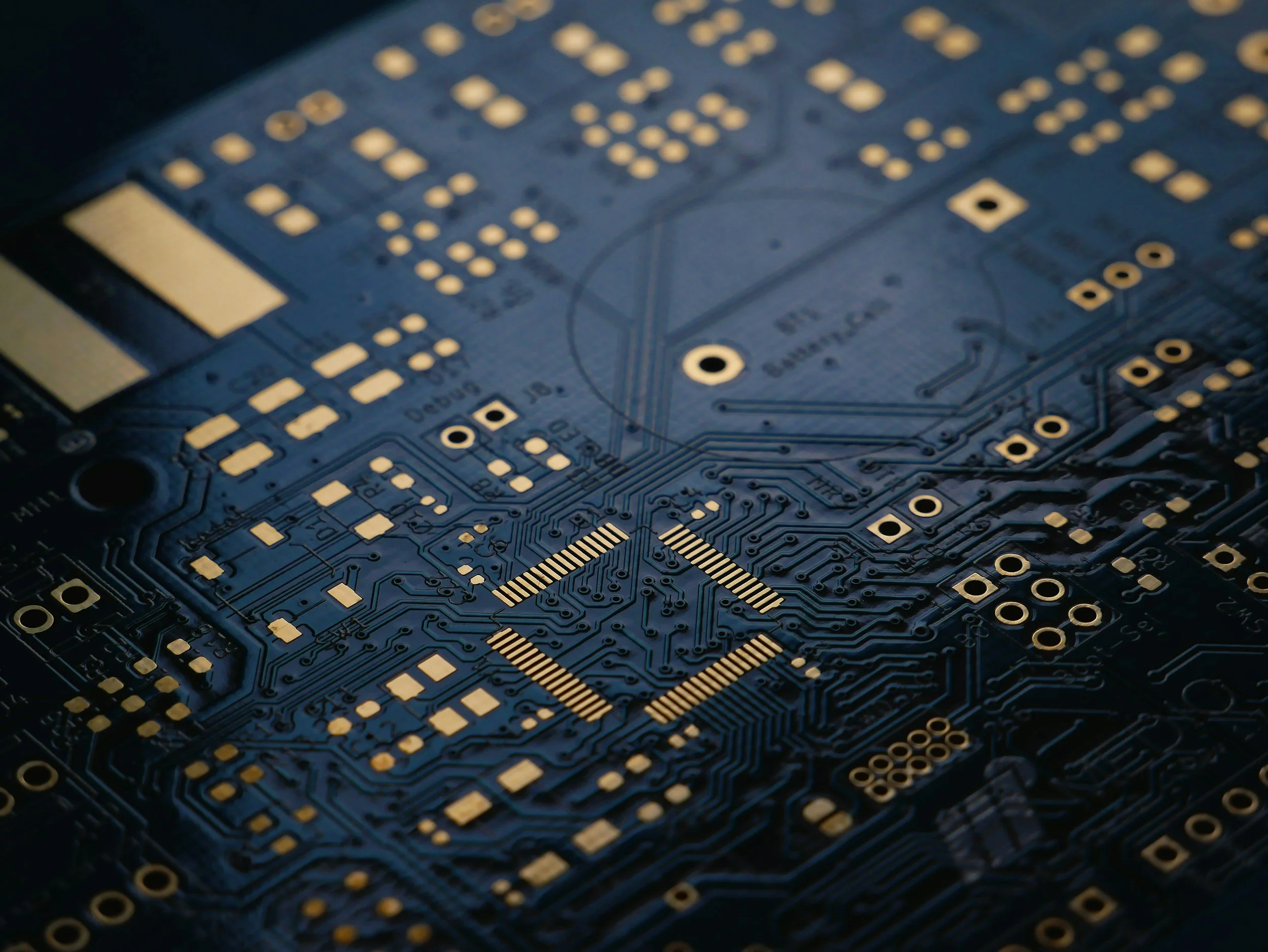 Close-up of a blue printed circuit board with gold contact points and electronic components.
